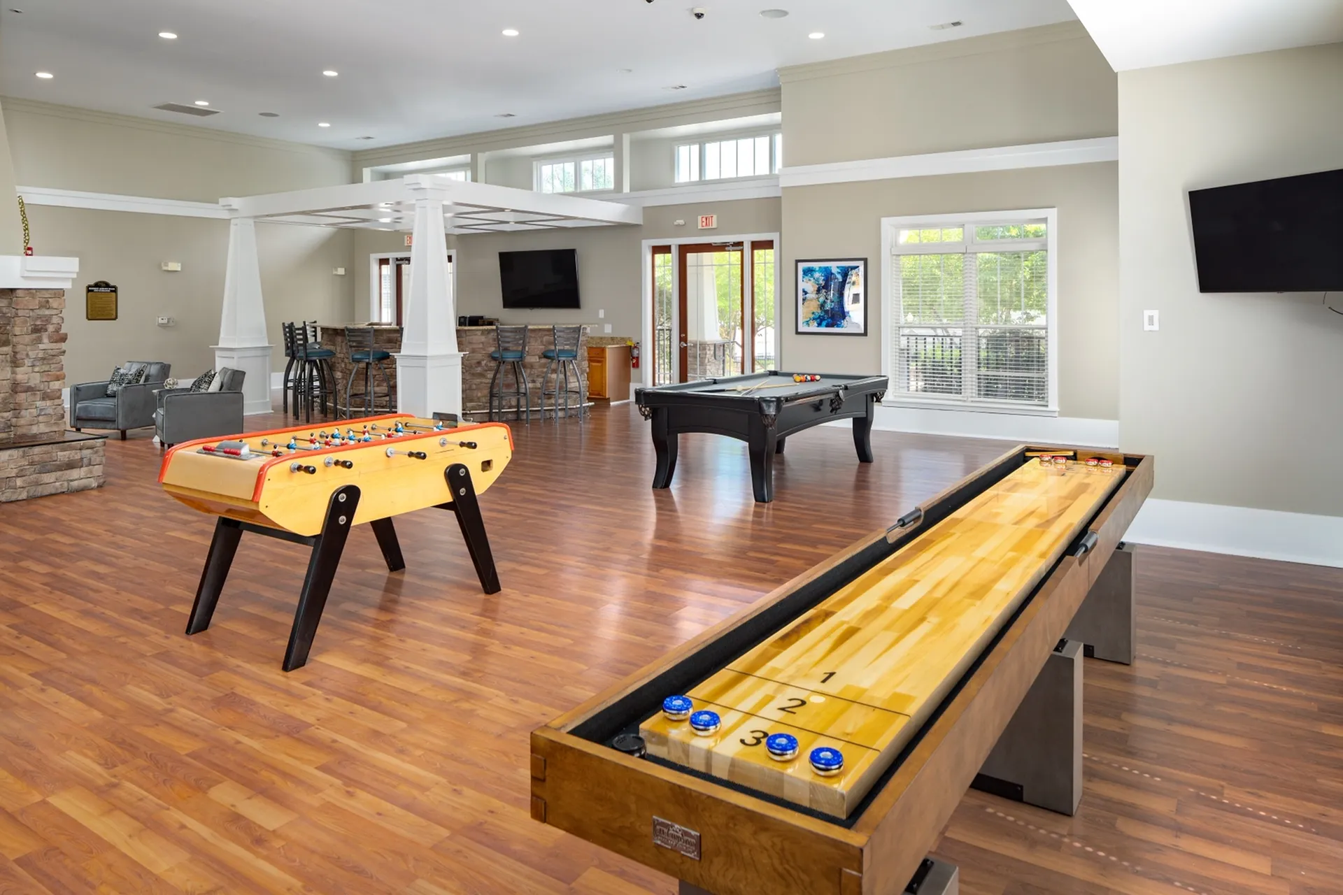 Elegant billiards room featuring a pool table, foosball table, and shuffleboard table. The space includes additional seating areas for relaxation or socializing at Abberly Place Apartments in Garner, NC