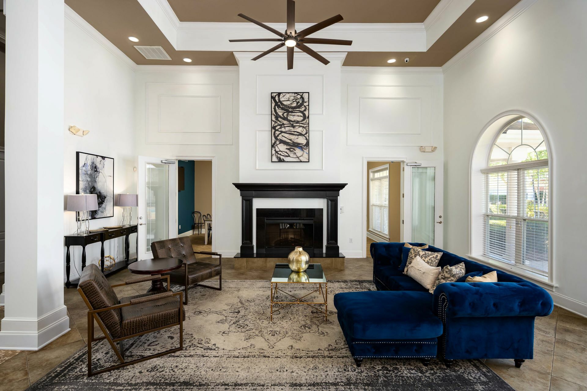 Elegant clubroom featuring a high ceiling, a cozy black fireplace, and large arched windows allowing natural light to brighten the space at Abberly Woods Apartments in Charlotte, NC