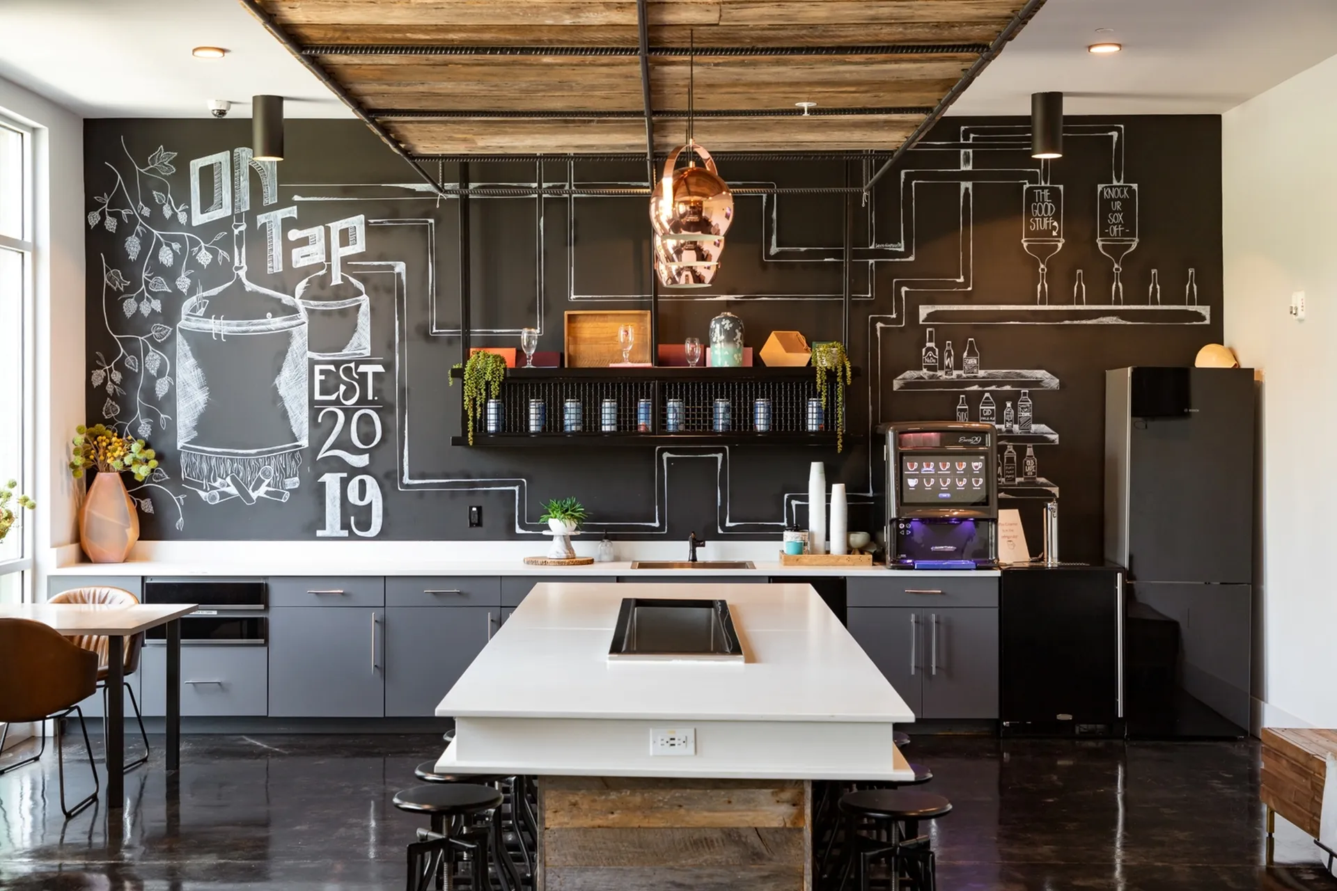 Trendy kitchen with modern design, featuring a blackboard wall with artistic chalk drawings, sleek cabinetry, and stylish pendant lighting.
