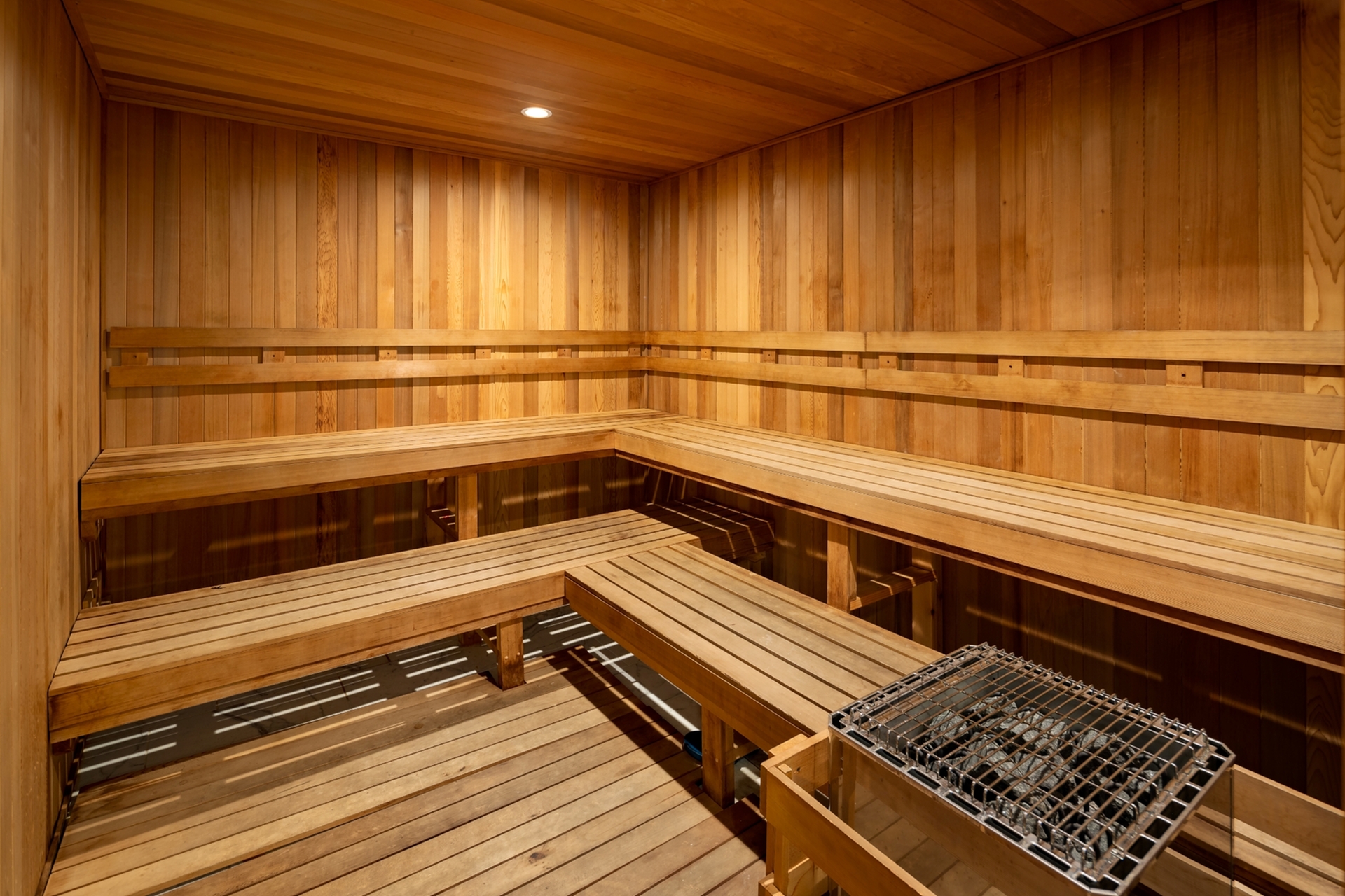 Luxurious wooden sauna room featuring sleek benches and a central heating unit, perfect for relaxation and rejuvenation.