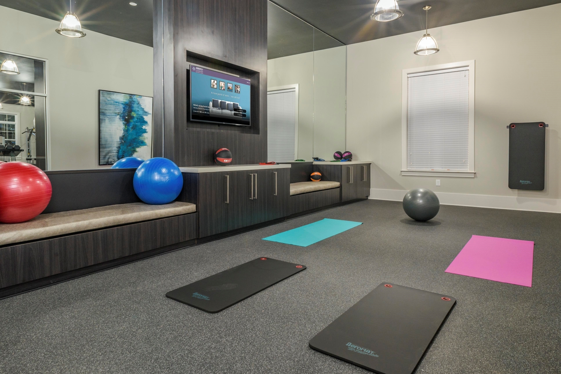 Modern fitness room with yoga mats, exercise balls, and sleek cabinetry, offering a stylish workout space.