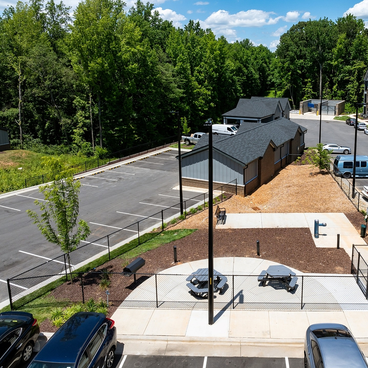 Charming apartment complex featuring modern buildings, ample parking, and lush greenery under a clear blue sky.