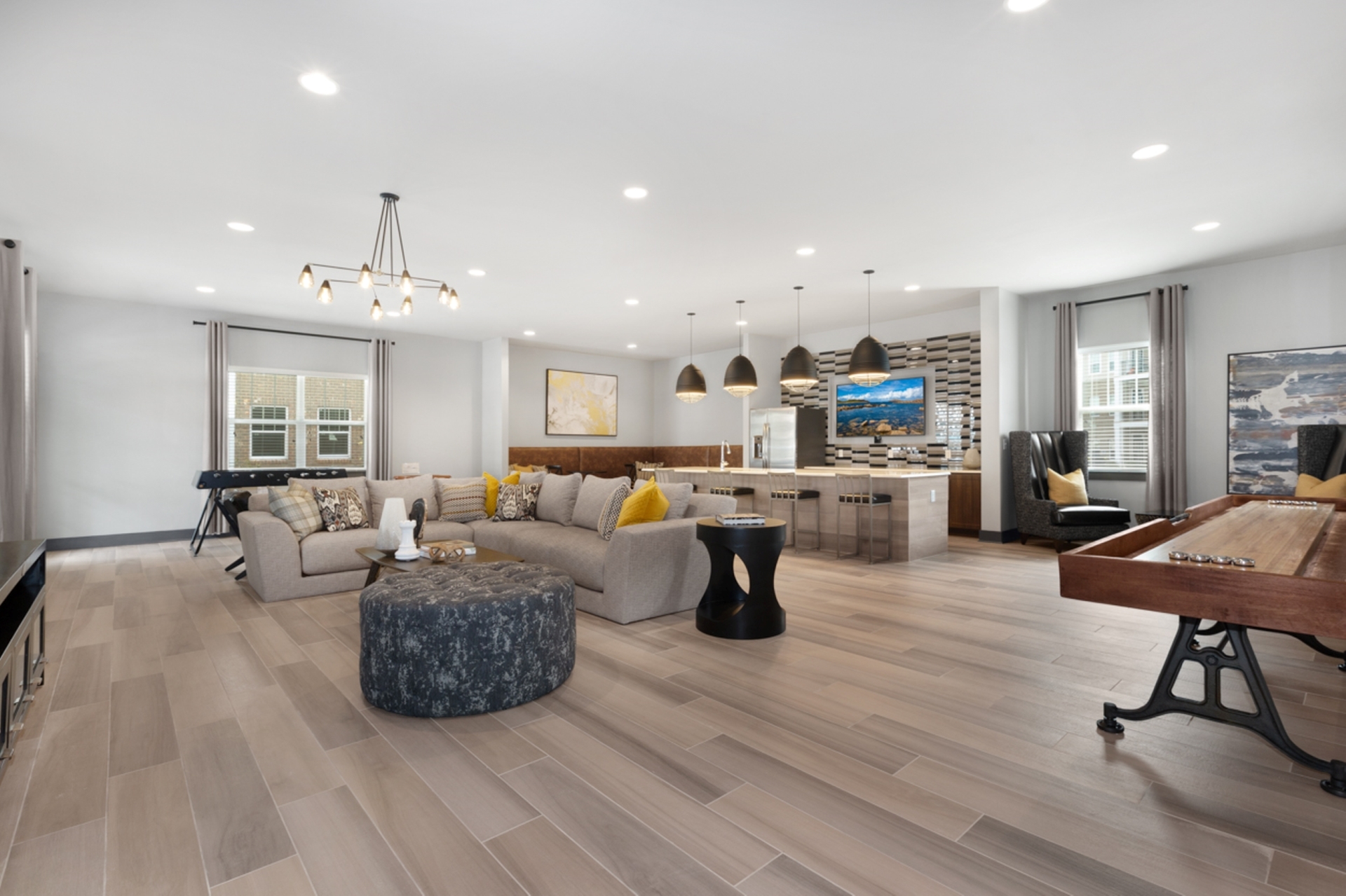 Modern open-concept living space with elegant lighting, cozy sectional sofa, stylish kitchen island, and sleek wood flooring.