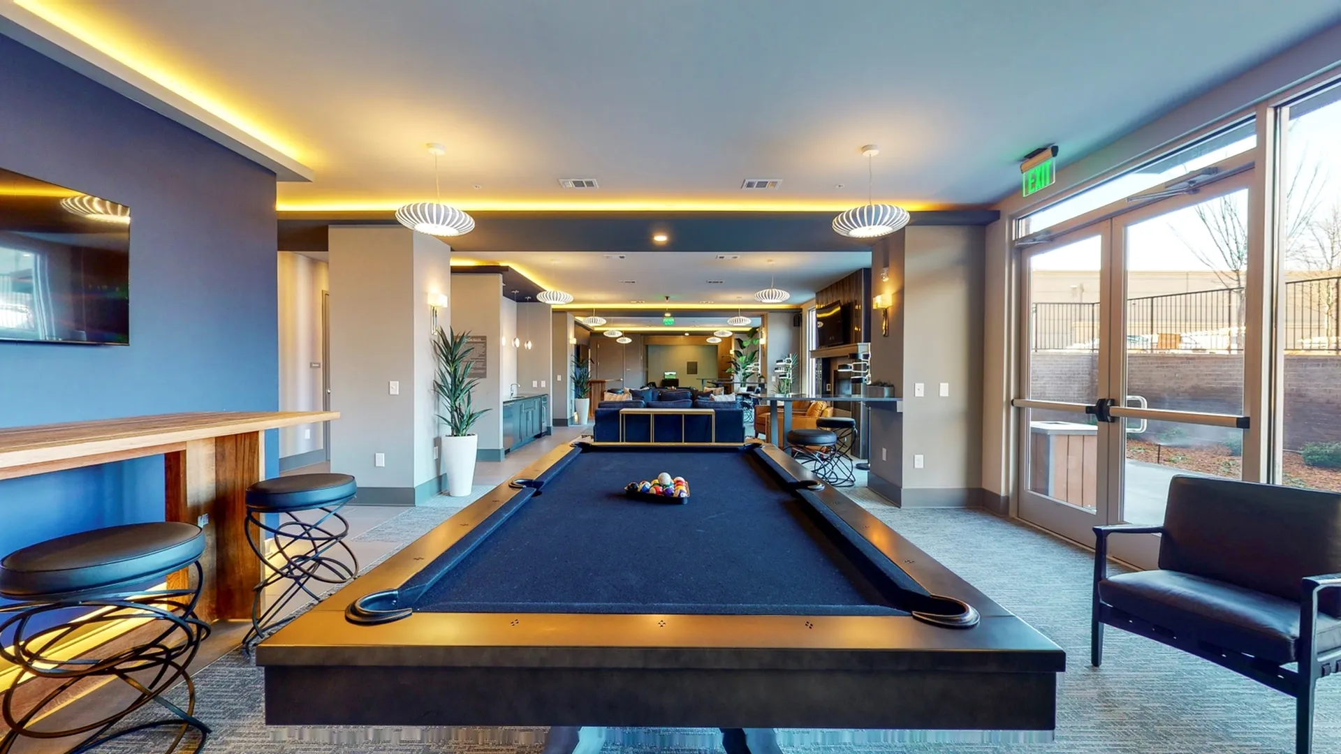 Luxurious clubhouse interior featuring a sleek billiards table, stylish seating, and modern lighting.