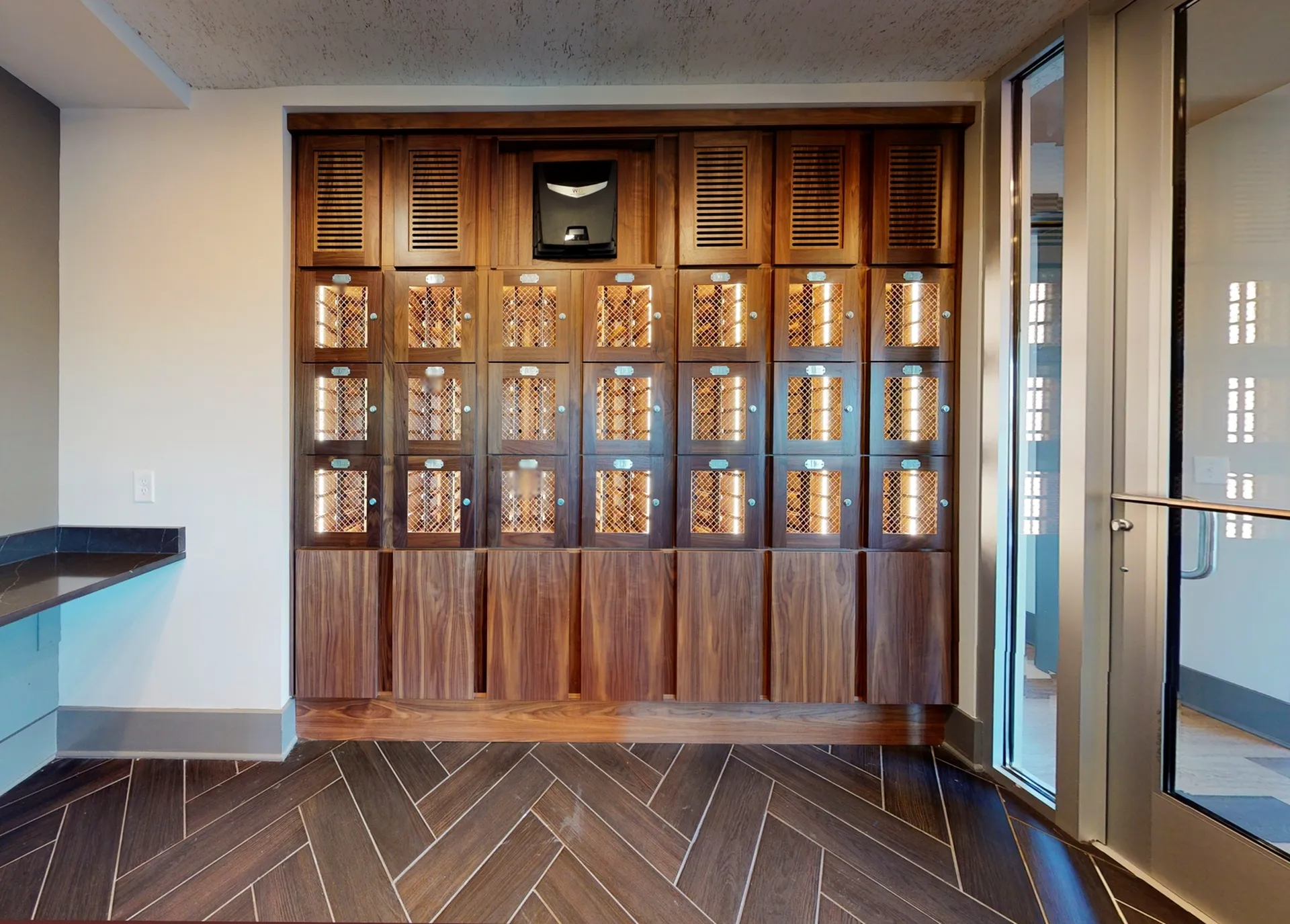 Chic apartment mailroom featuring stylish wooden lockers and contemporary herringbone flooring.