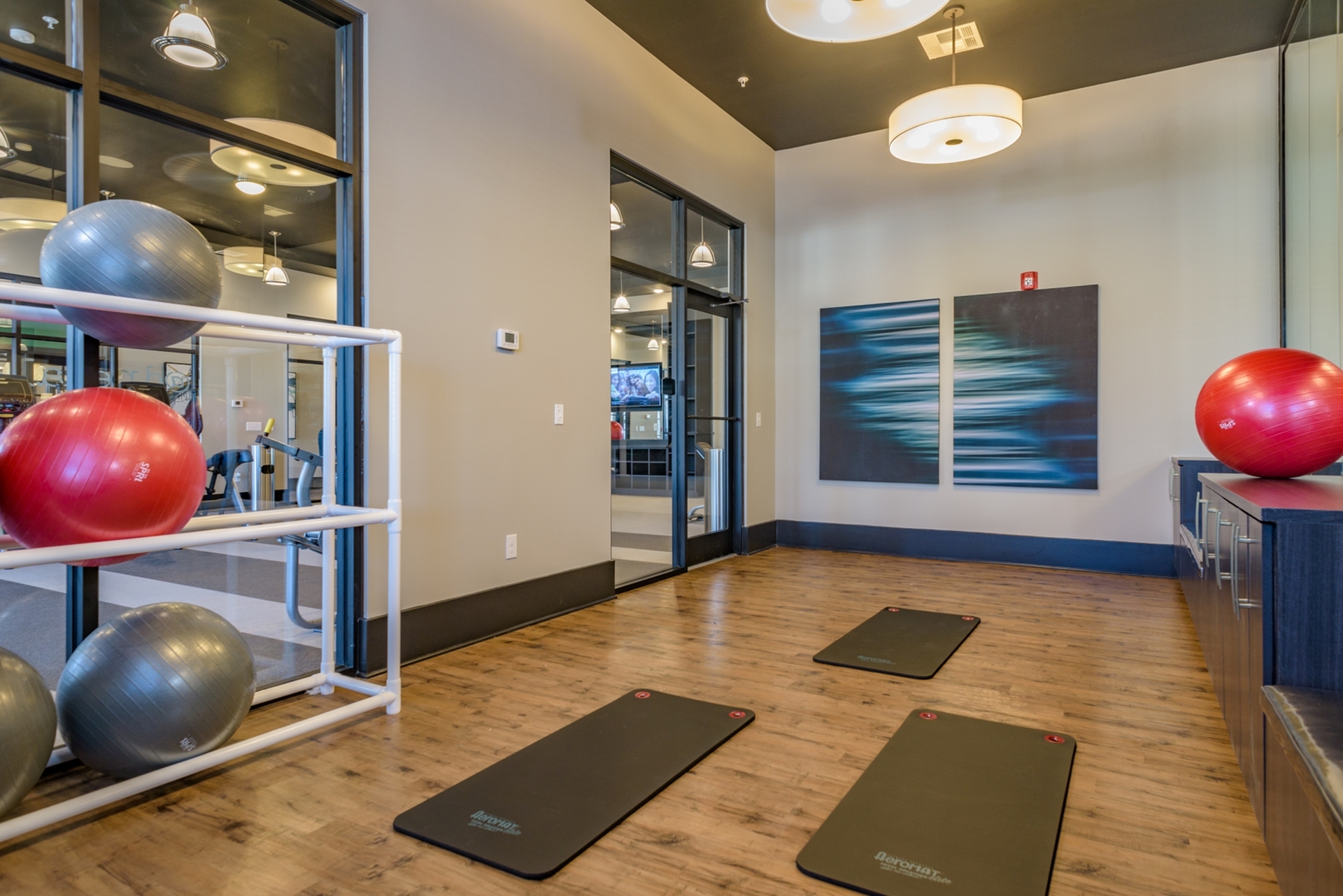 Modern apartment gym with yoga mats and exercise balls, featuring stylish decor and ample natural light.