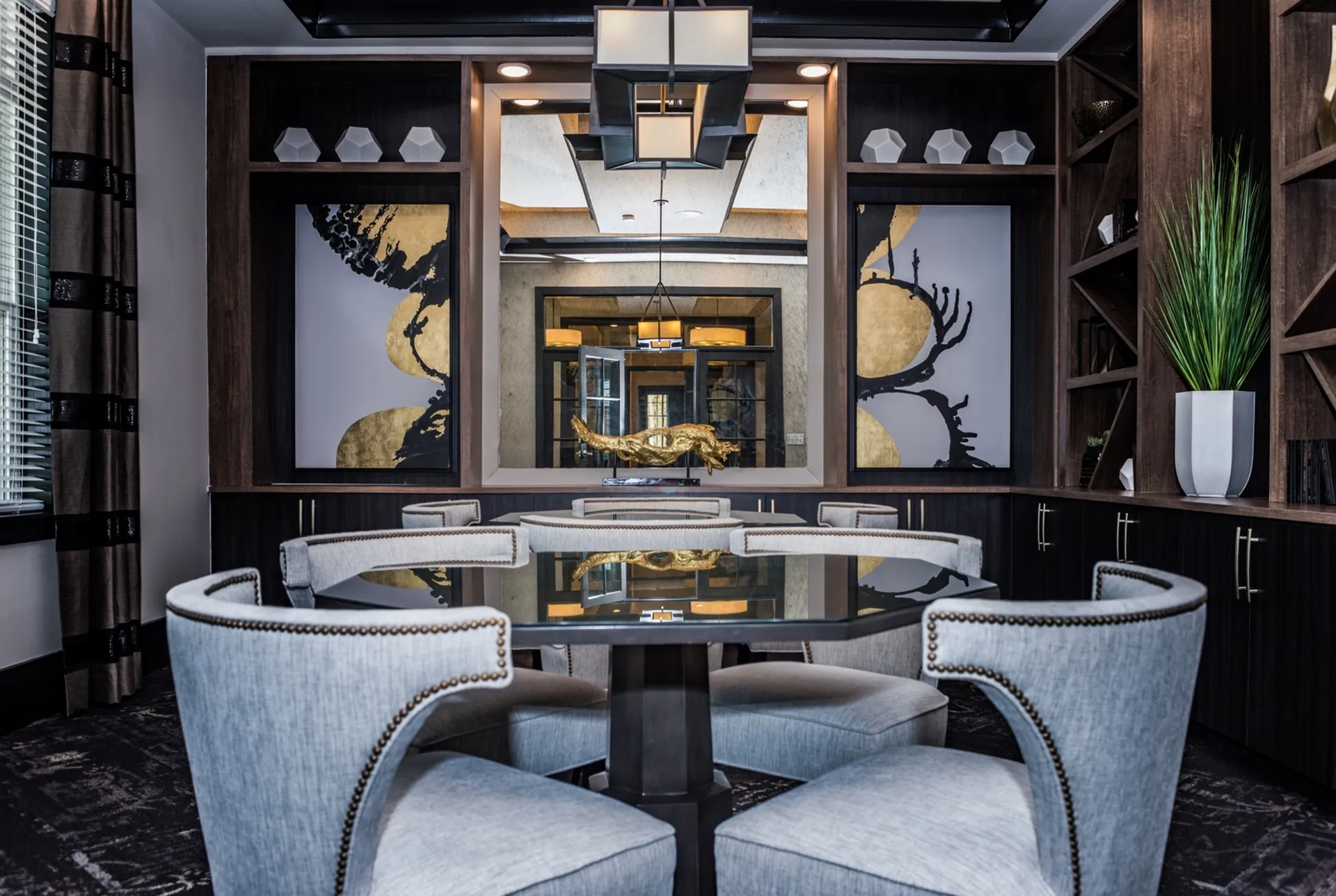 Elegant dining room with a chic glass-top table, plush grey chairs, and modern art accents, creating a sophisticated atmosphere.