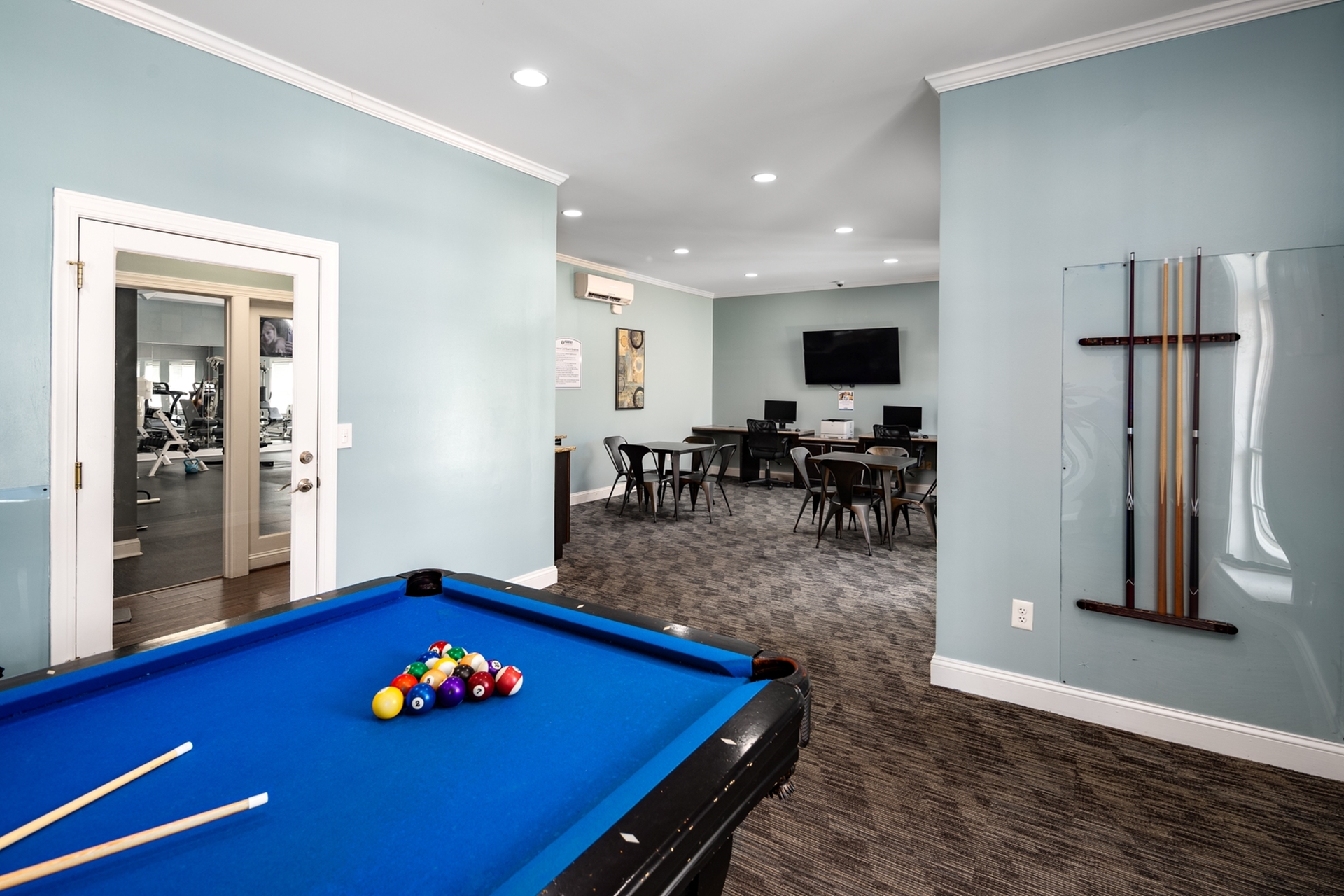 Inviting recreation room showcasing a billiards table, modern workstations, and cozy seating area, ideal for both relaxation and productivity.