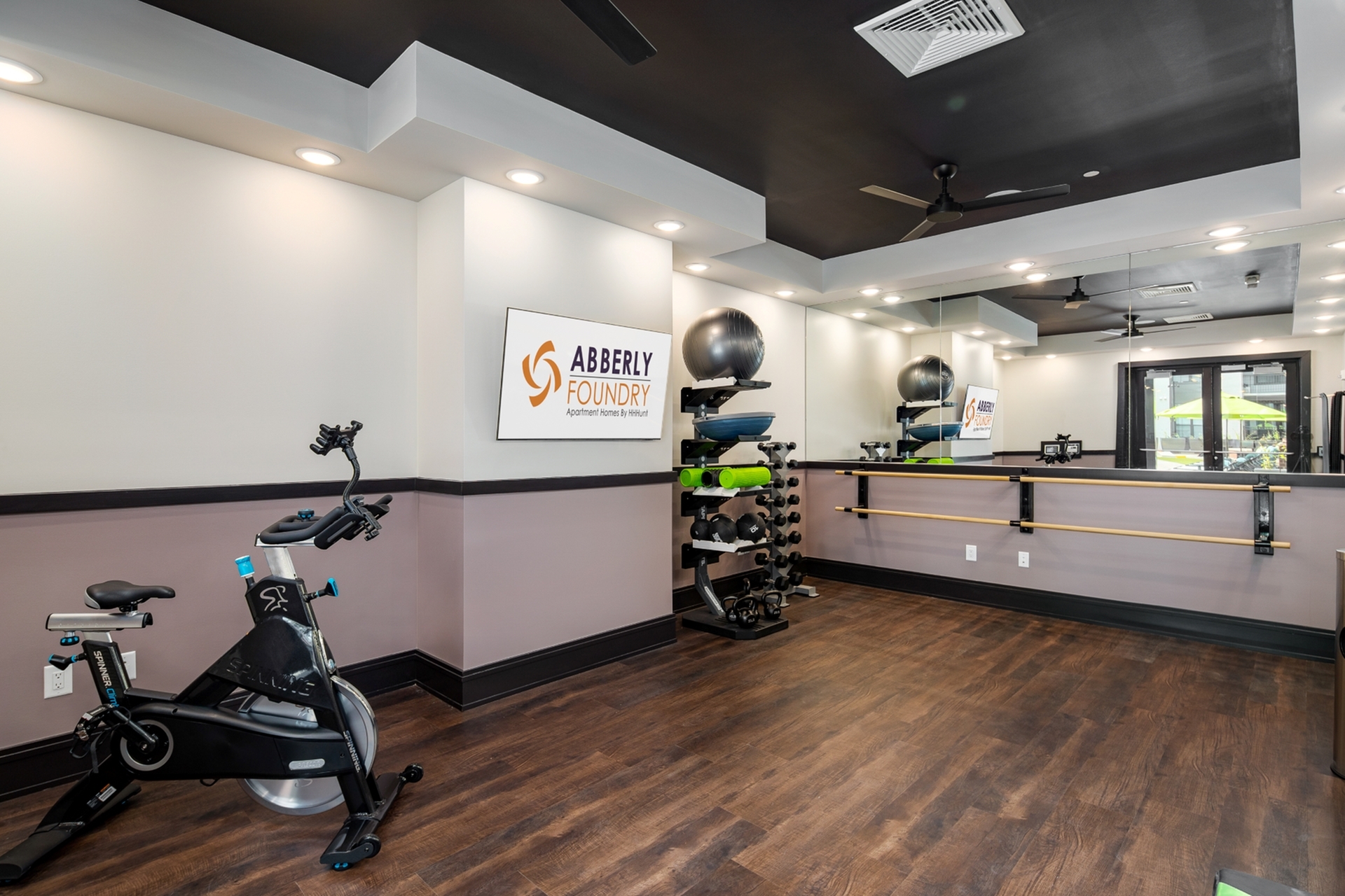 Modern fitness center with sleek design featuring exercise bike, free weights, and large mirrors at Abberly Foundry Apartments.