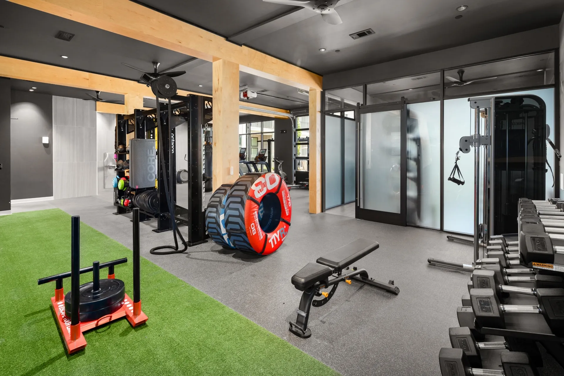 Modern fitness center with state-of-the-art equipment, vibrant green turf, and spacious workout area for a dynamic exercise experience.