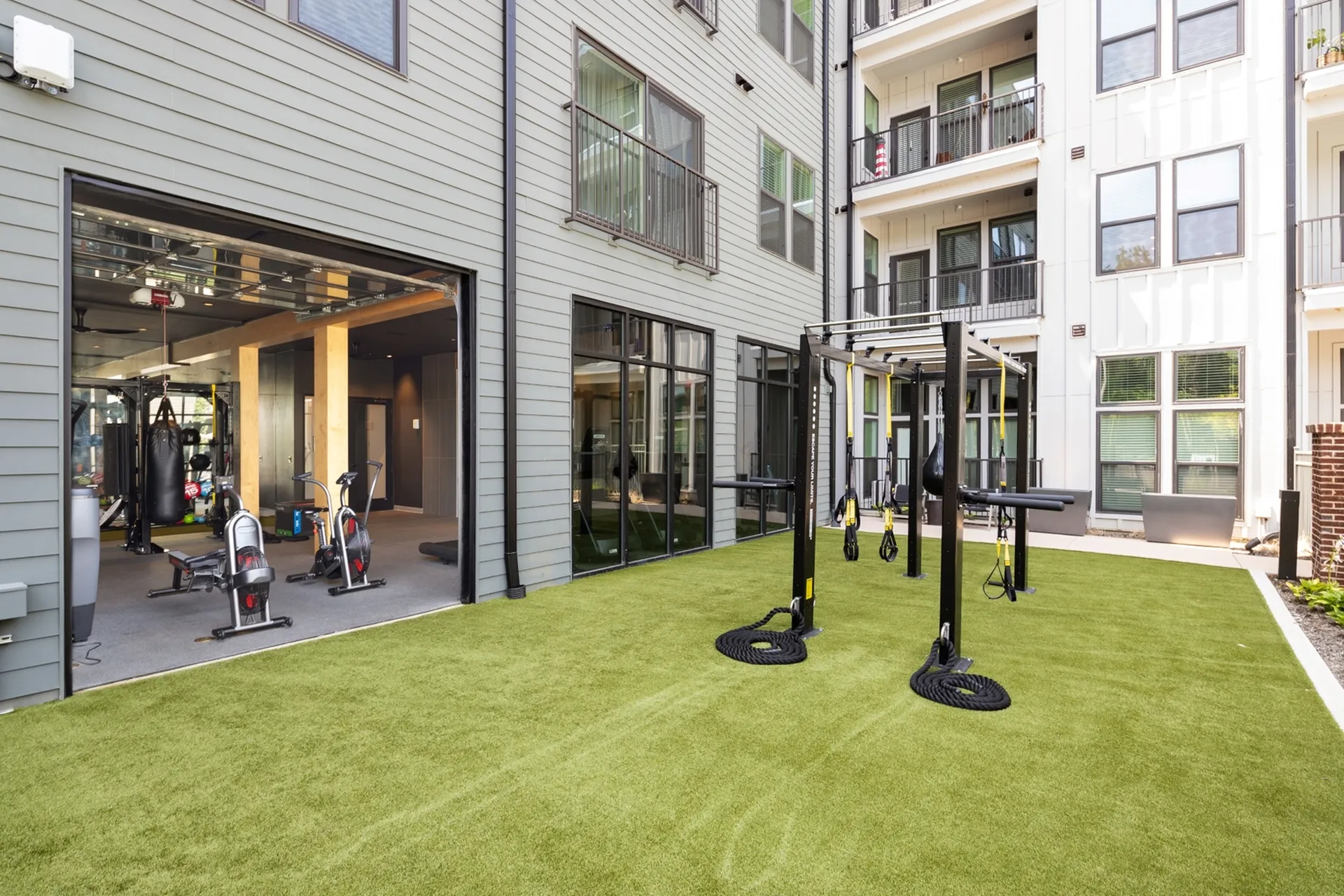 Modern apartment complex with outdoor fitness area and indoor gym featuring exercise equipment, perfect for active lifestyles.