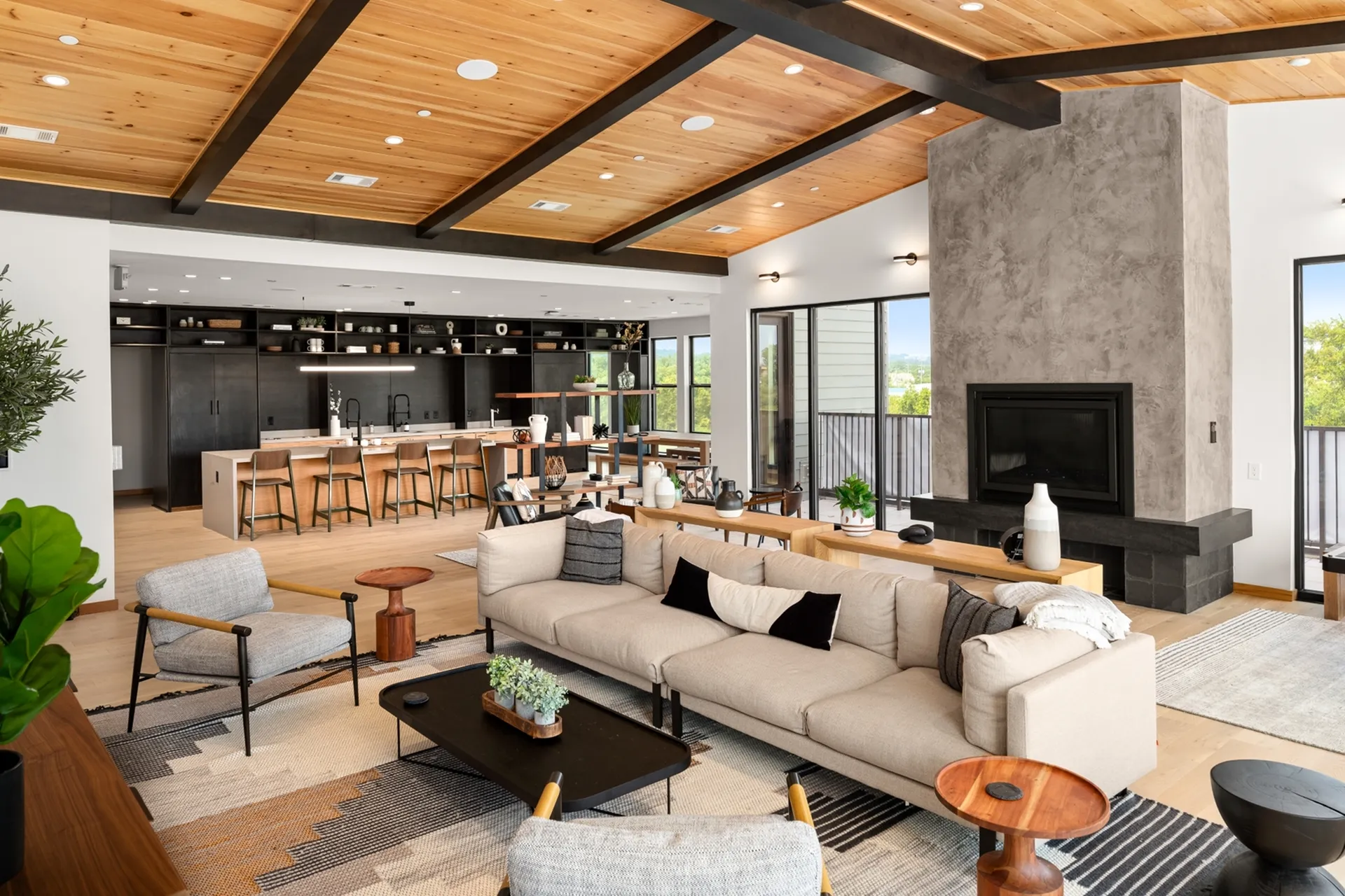 Luxurious open-concept living room with a stylish wooden ceiling, cozy fireplace, and modern kitchen bar with sleek counter seating.