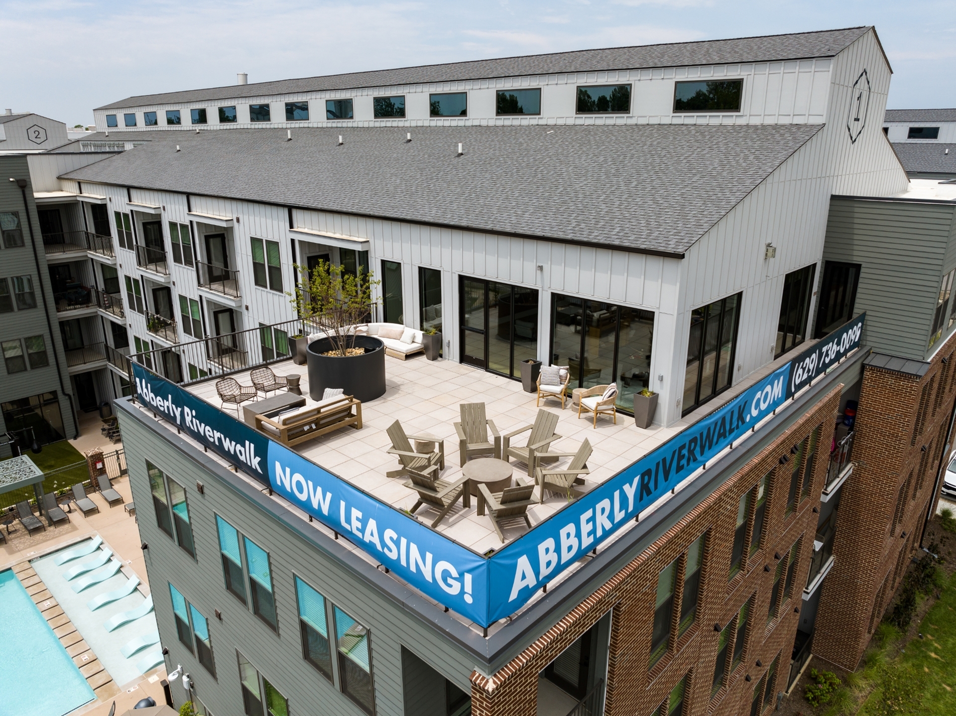 Modern apartment with spacious rooftop patio, stylish seating, and pool view, now leasing at Abberly Riverwalk.