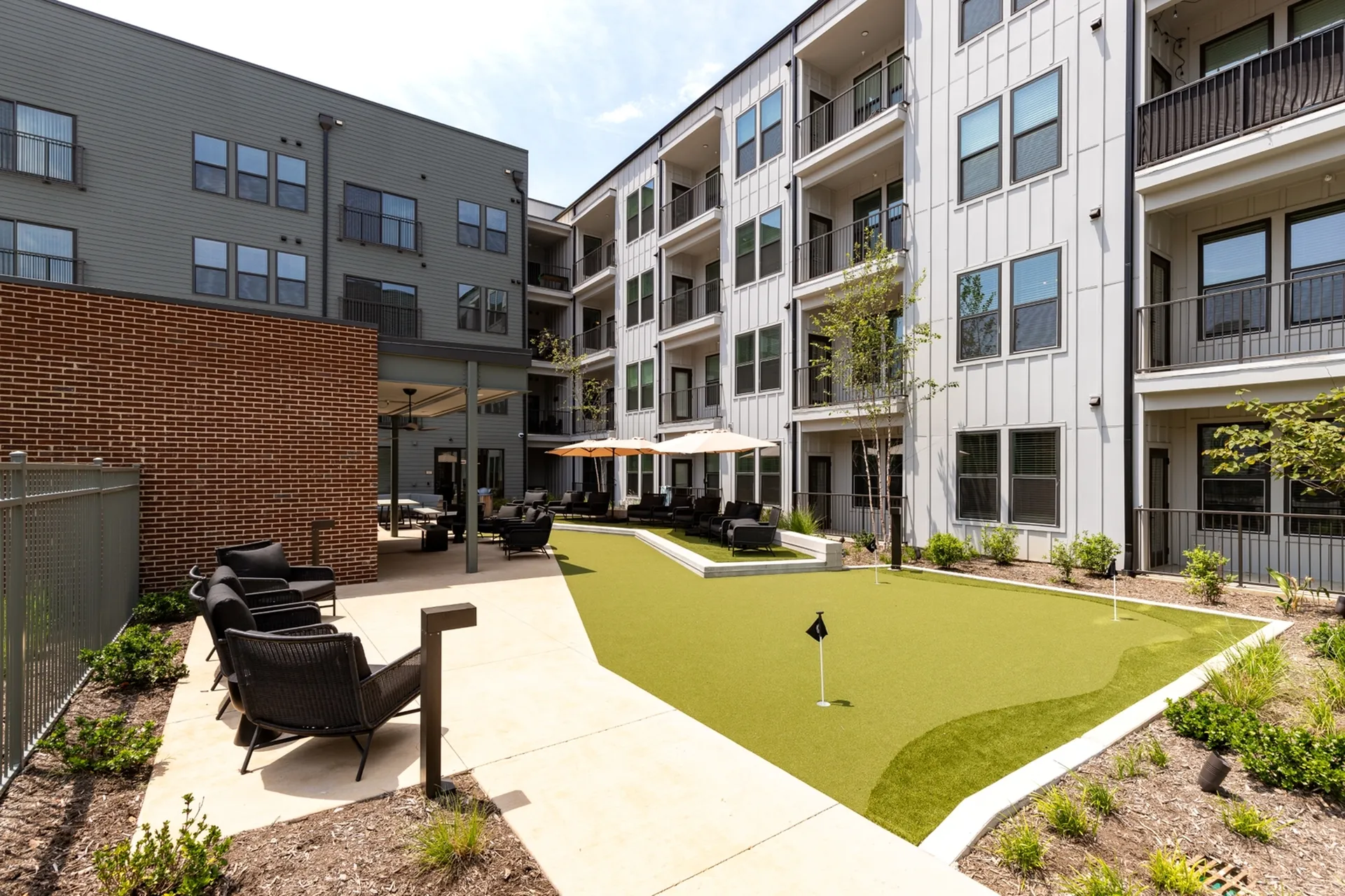 Modern apartment complex with cozy outdoor seating area and putting green, perfect for relaxation and leisure.