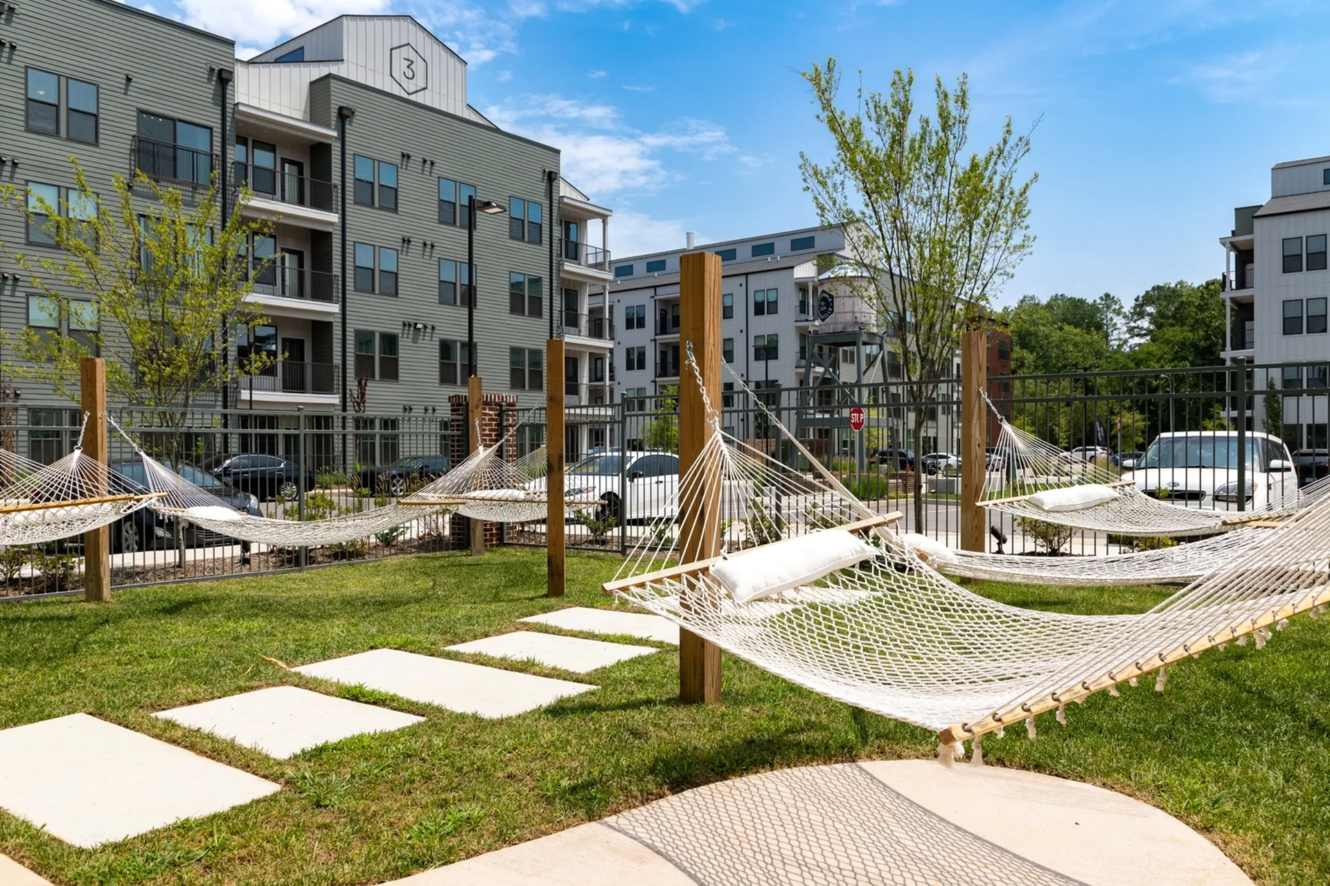 Modern apartment complex with inviting outdoor hammock relaxation area, surrounded by lush greenery and stylish architecture.