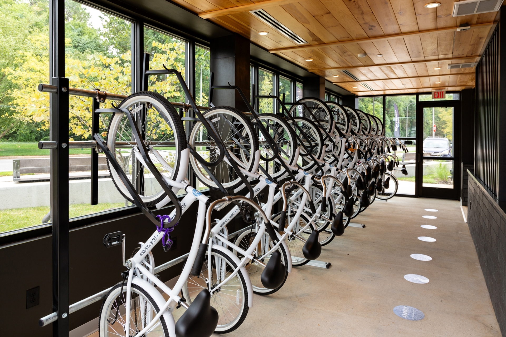 Bright and modern bike storage room with neatly arranged bicycles and large windows accentuating natural light.