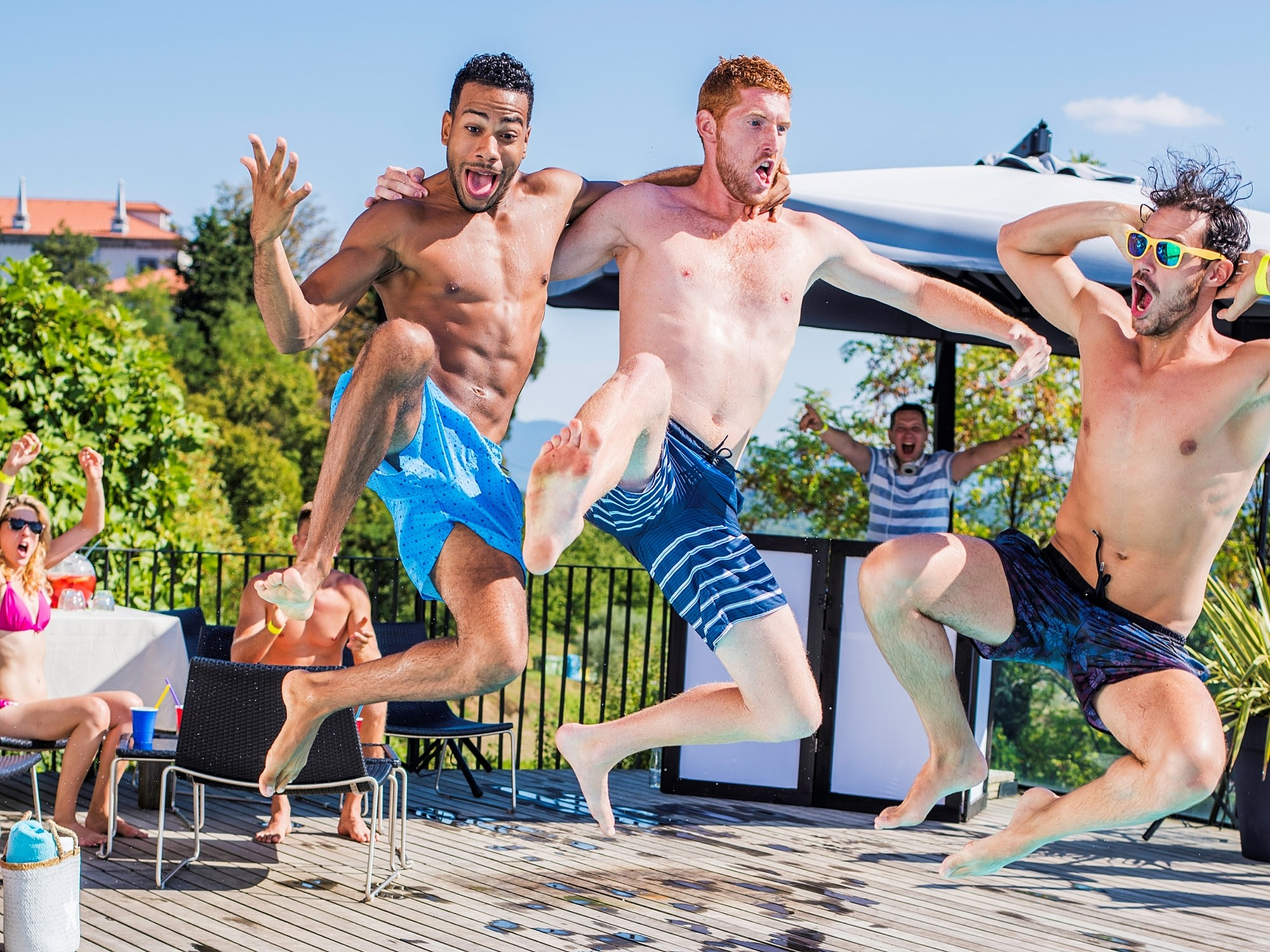 Vibrant summer poolside fun with joyful friends jumping into a crystal-clear swimming pool, capturing the essence of relaxation and excitement.