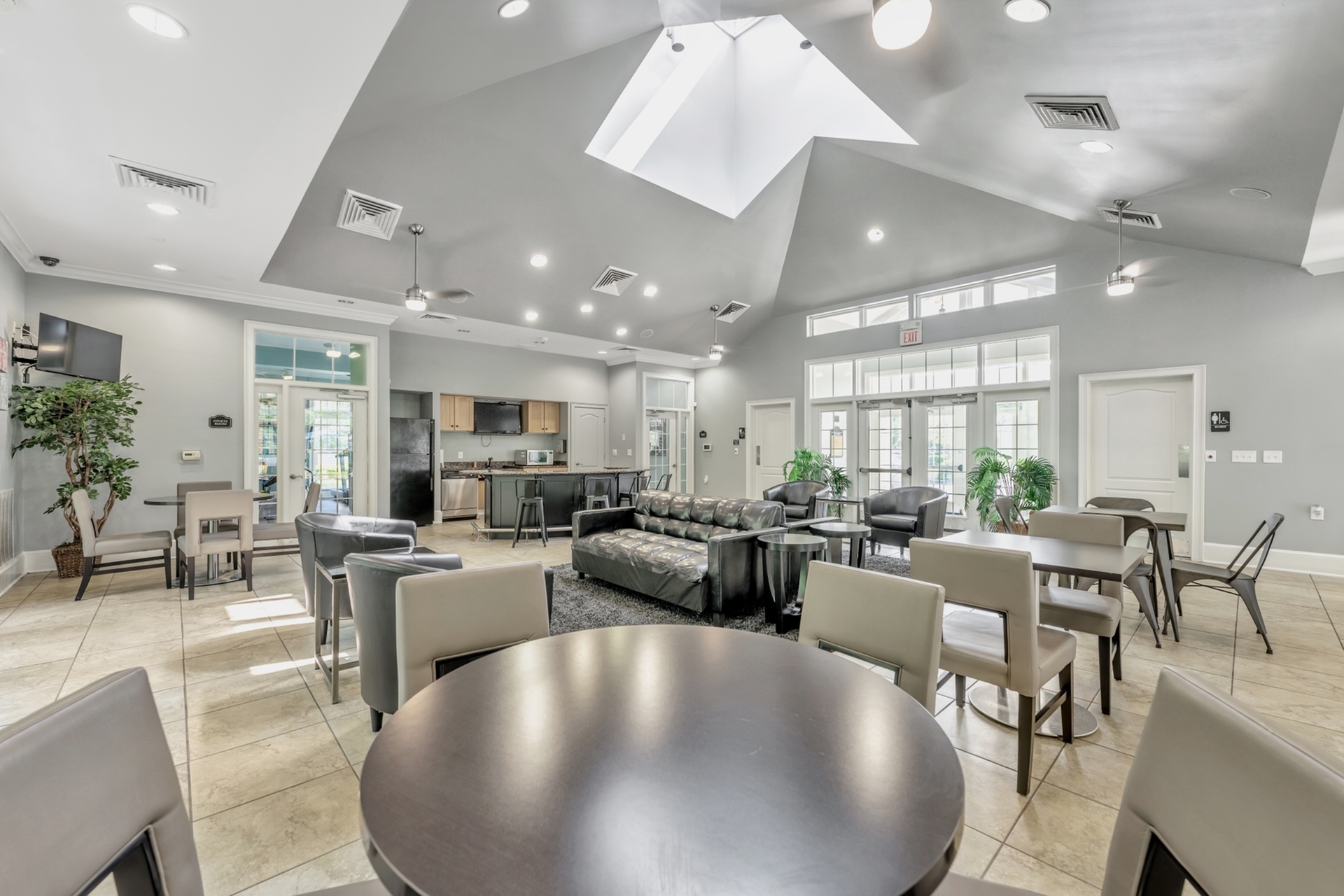 Bright and welcoming community lounge with modern seating, kitchenette, and ample natural light from skylights.