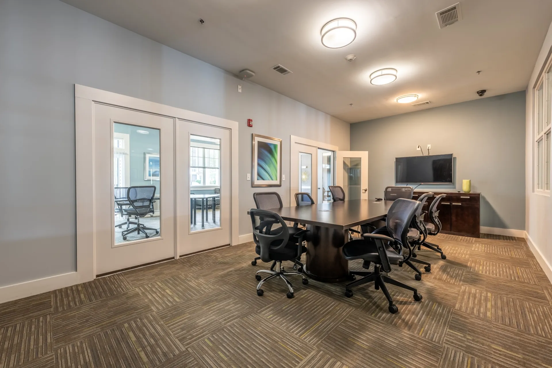 Modern meeting room with a sleek conference table, stylish chairs, and a wall-mounted television, ideal for productive gatherings.