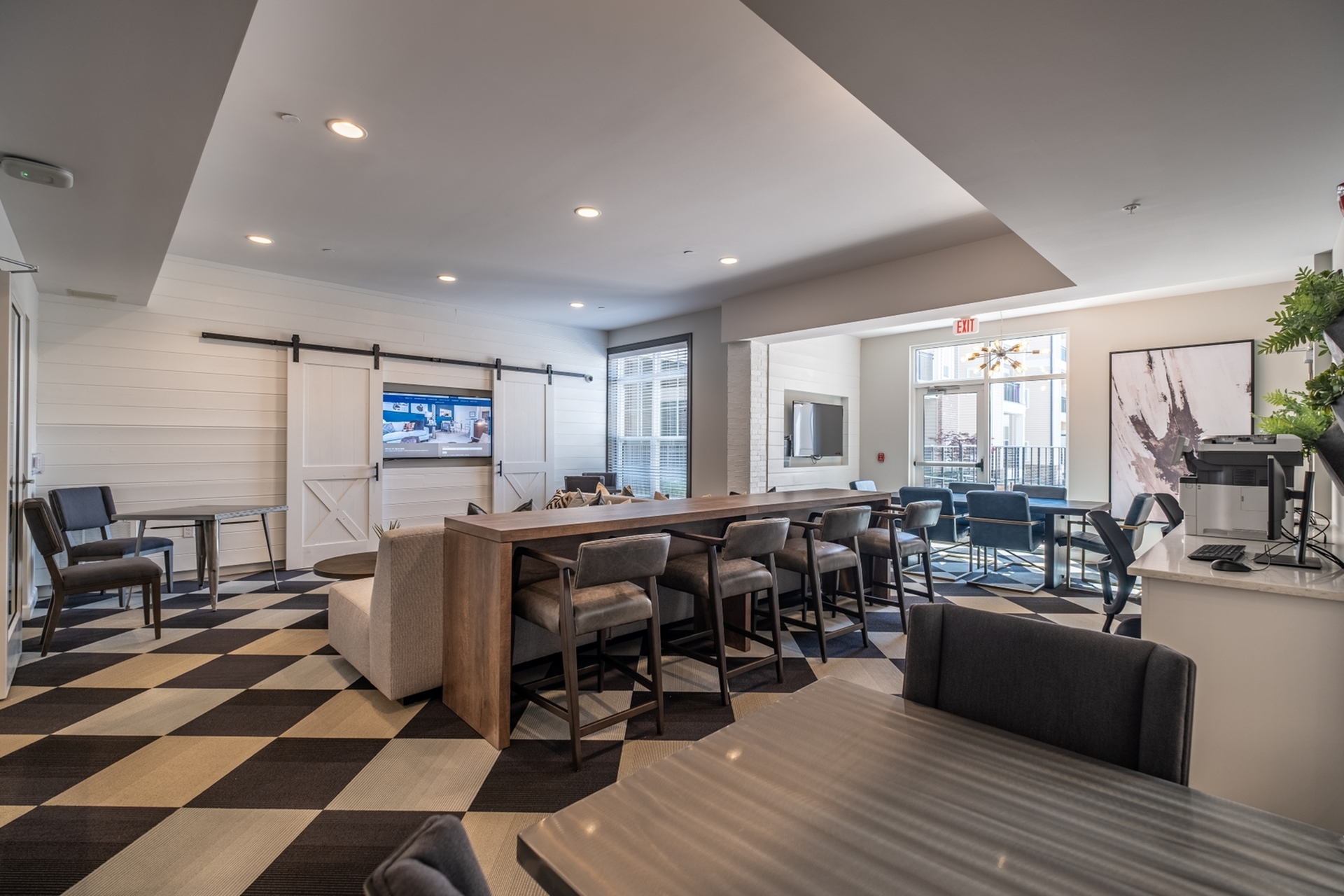 Modern communal lounge with a chic checkerboard floor, stylish seating area, and large wall-mounted TV, inviting for social gatherings and relaxation.