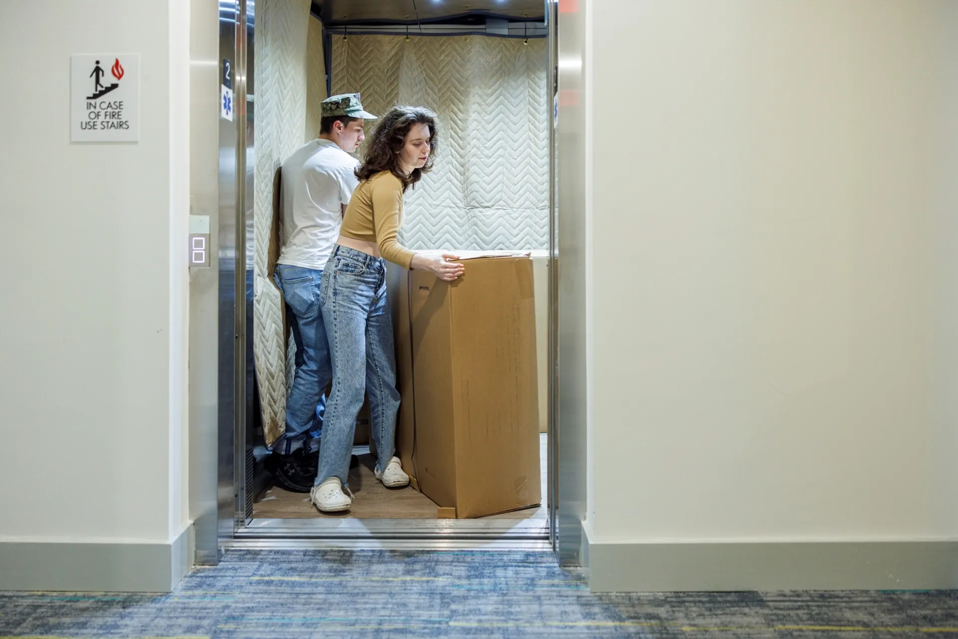 Modern apartment elevator with movers handling a large box, showcasing convenience and accessibility for residents.