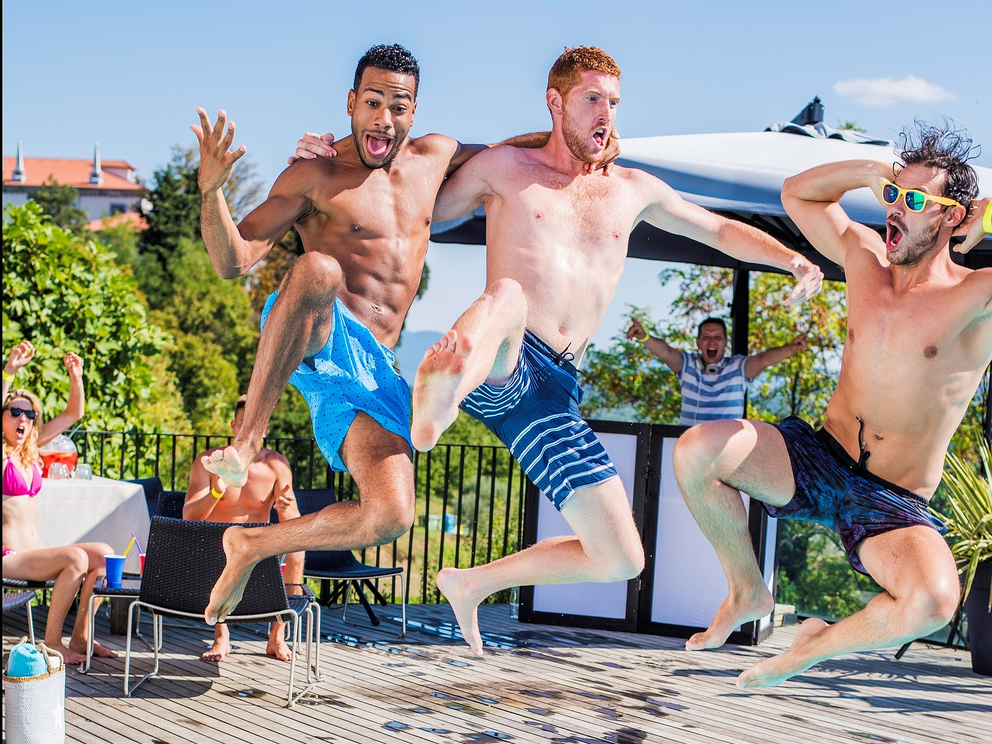 Vibrant pool party scene with three energetic friends jumping into a sparkling blue pool, surrounded by lush greenery and sunny skies.