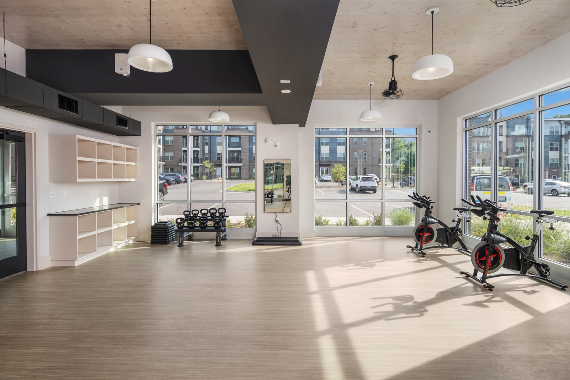 Bright and modern fitness center with large windows, spin bikes, and kettlebells, offering a welcoming exercise space.