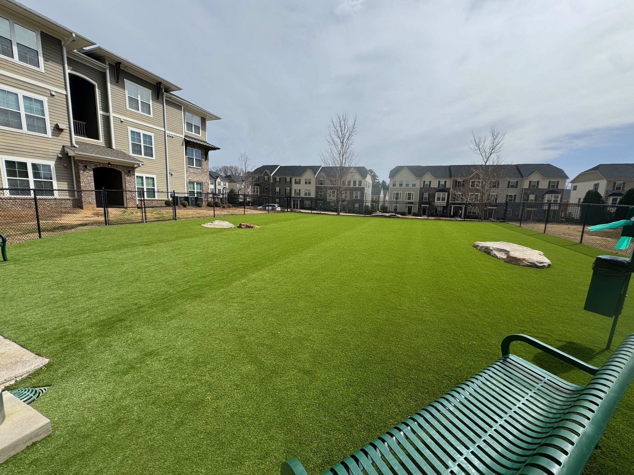 Inviting apartment complex with lush green communal lawn and modern architecture, perfect for outdoor relaxation.