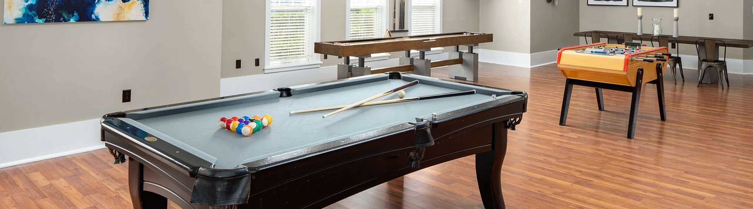 Spacious game room featuring a variety of recreational options, including a pool table, shuffleboard, and foosball table at Abberly Place Apartments in Garner, NC