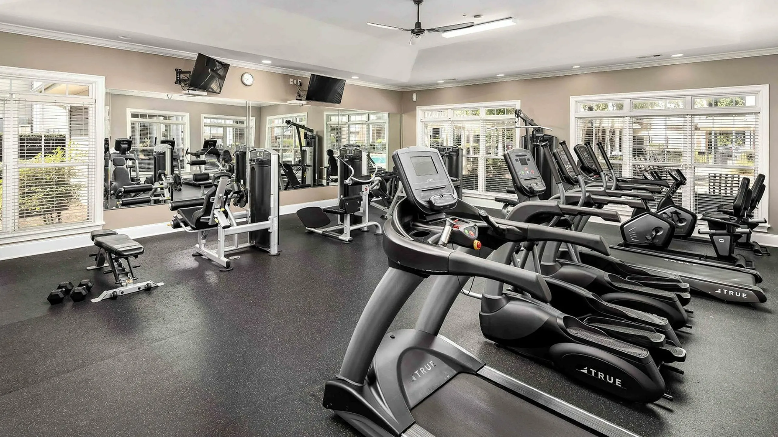 Bright and modern fitness center featuring a variety of cardio machines, including treadmills and ellipticals, along with strength training equipment, free weights, and mirrored walls at Abberly Woods Apartments in Charlotte, NC