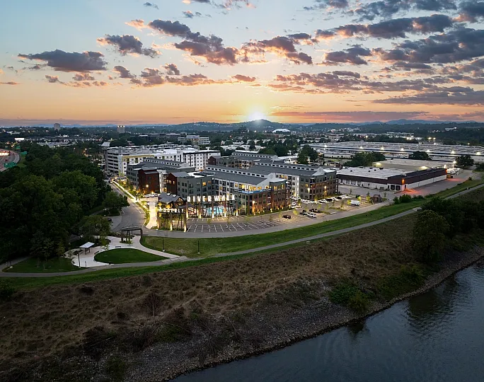 Stunning aerial view of Riverwalk community at sunset, showcasing modern architecture, vibrant landscaping, and a serene riverside location.