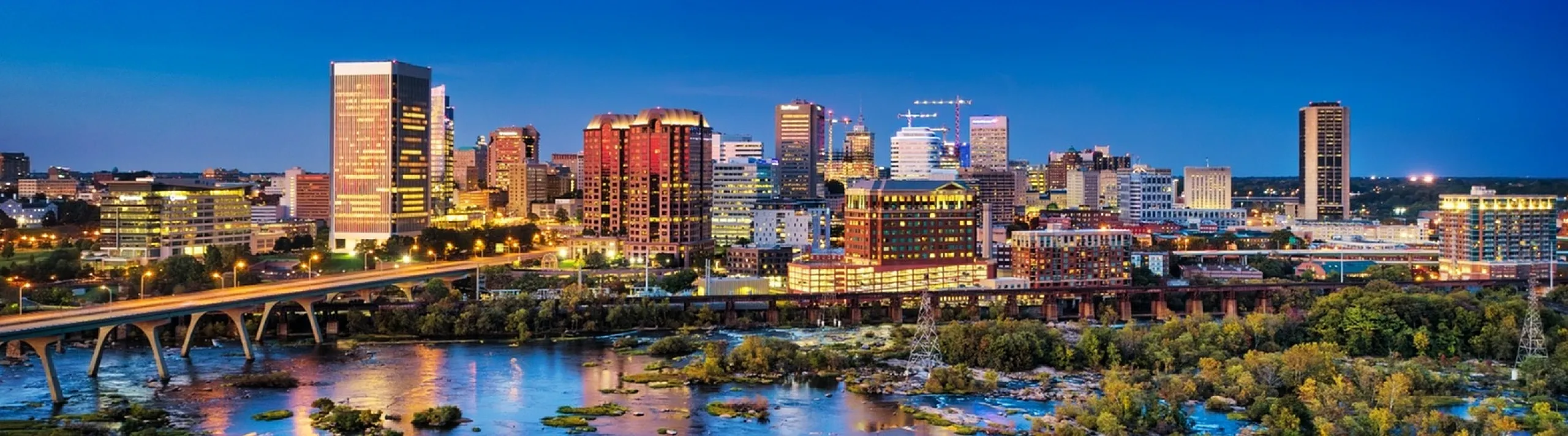 Vibrant cityscape with a stunning skyline, illuminated buildings reflecting on a scenic river, perfect for modern urban living.