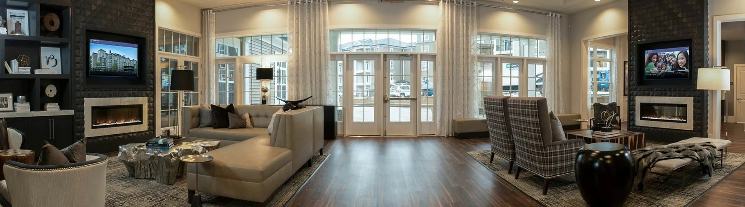 Elegant lounge area with modern design, featuring cozy armchairs, stylish sofas, two wall-mounted TVs, and sleek fireplaces, ideal for relaxation and social gatherings.