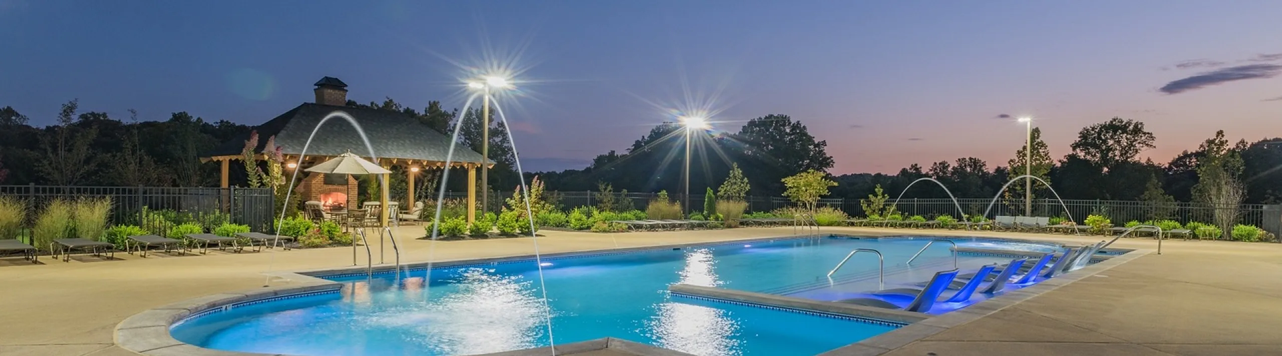 Elegant twilight poolside setting with serene water features, cozy gazebo, and ambient lighting perfect for relaxation.