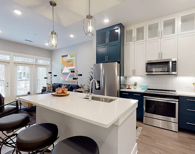 Modern open-concept kitchen and living area with sleek white and navy cabinetry, stylish island, and abundant natural light.
