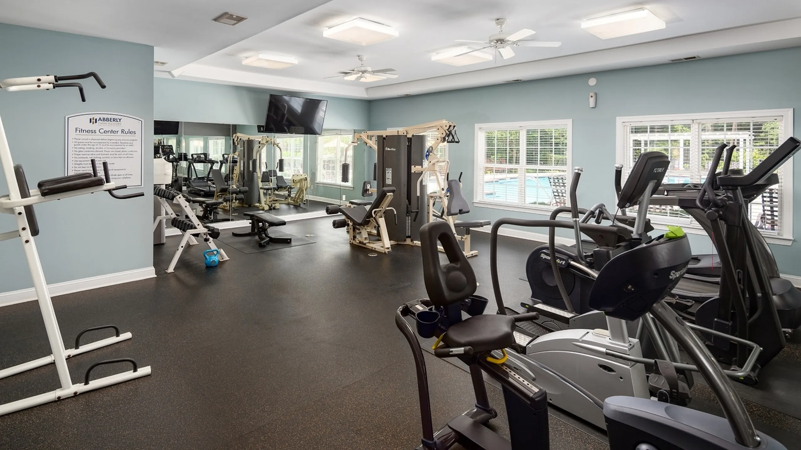 Bright and modern fitness center featuring state-of-the-art exercise equipment and large windows with a view of the pool.