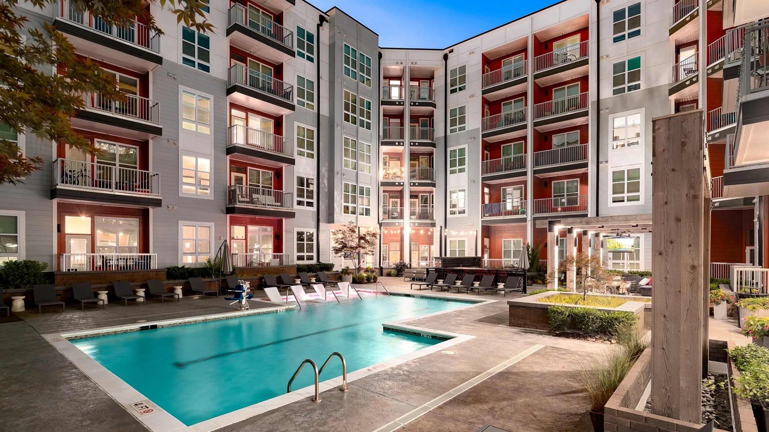 Modern apartment complex with luxurious pool, inviting lounge chairs, and elegant balconies, perfect for stylish urban living.
