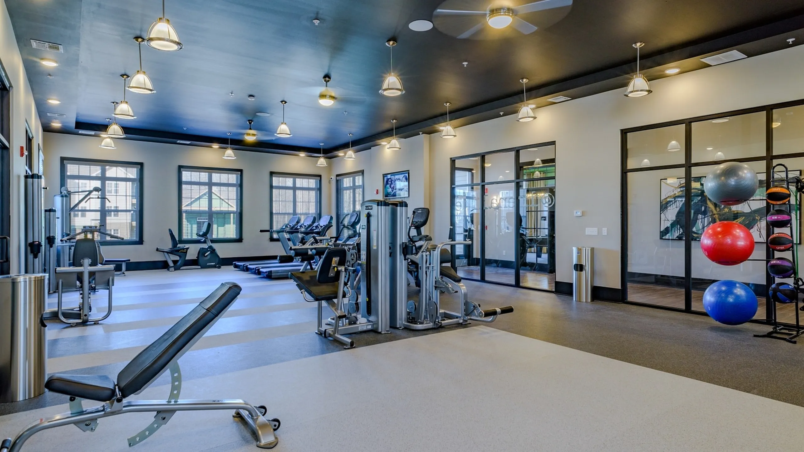 Bright and modern fitness center featuring state-of-the-art exercise equipment, ample natural light, and a sleek, contemporary design.