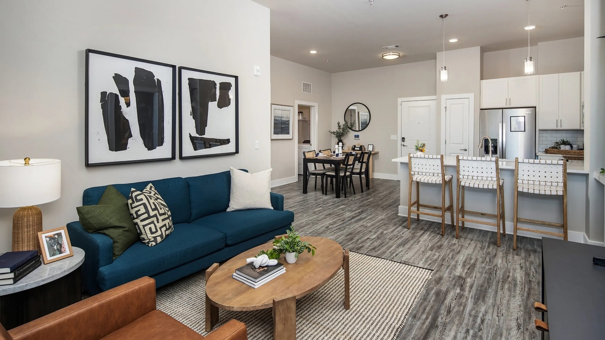 Contemporary open-plan living space featuring a chic blue sofa, stylish decor, and a sleek kitchen with a breakfast bar.
