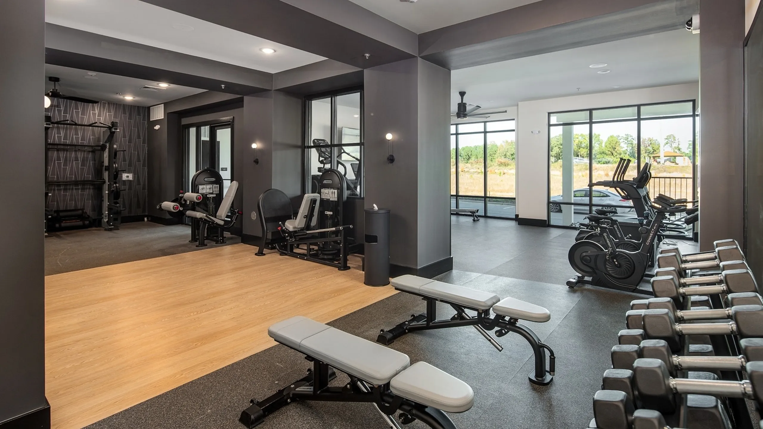 Modern gym with state-of-the-art fitness equipment, spacious layout, and scenic views through large windows.