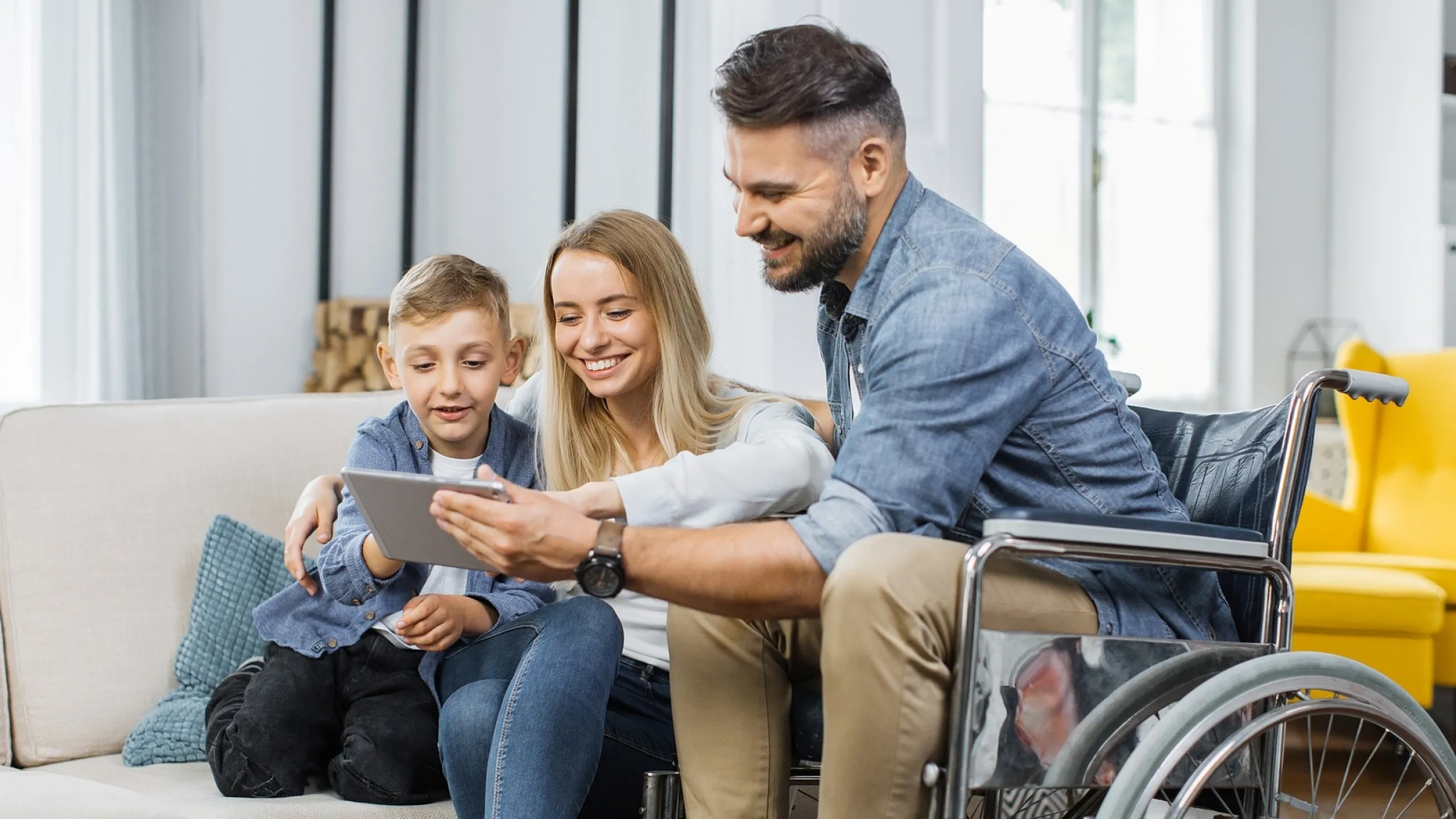Happy family enjoying time together on a cozy sofa in a bright, modern living room, featuring a wheelchair accessible space filled with warmth and natural light.