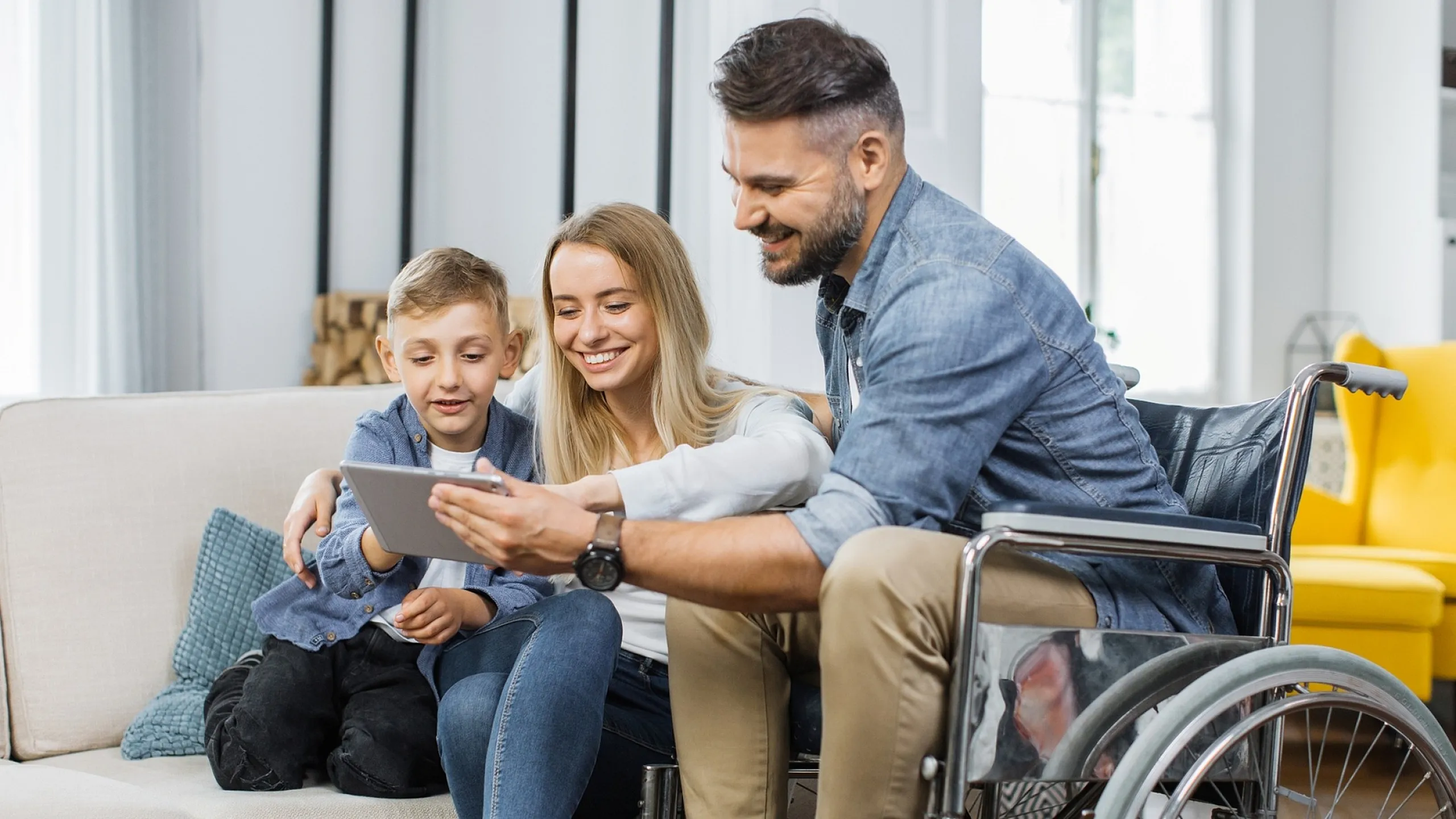 Happy family enjoying quality time in a modern, accessible living room while engaging with a tablet.