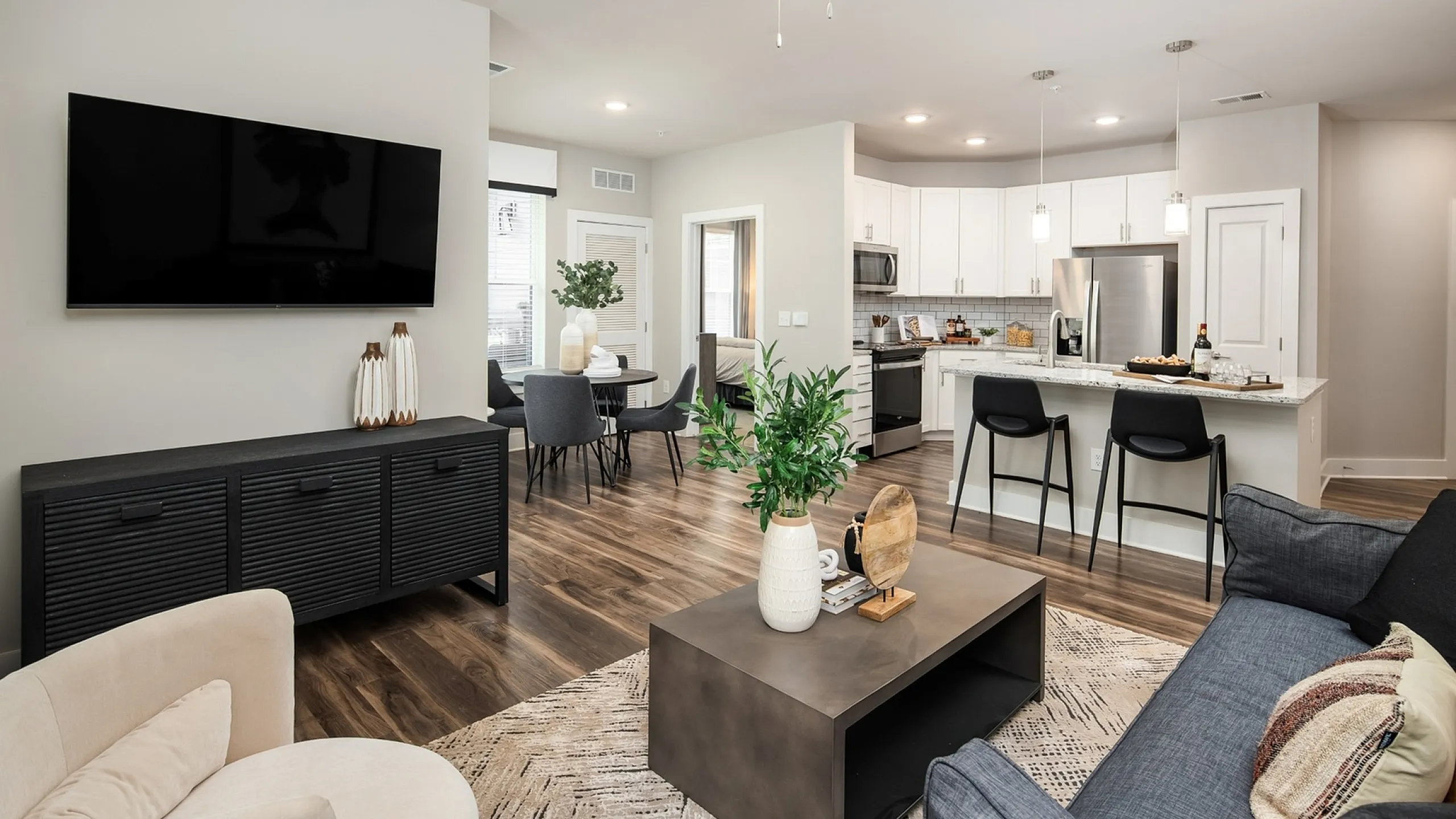 Modern open-concept living room with sleek kitchen, cozy dining area, and bright decor, perfect for stylish urban living.