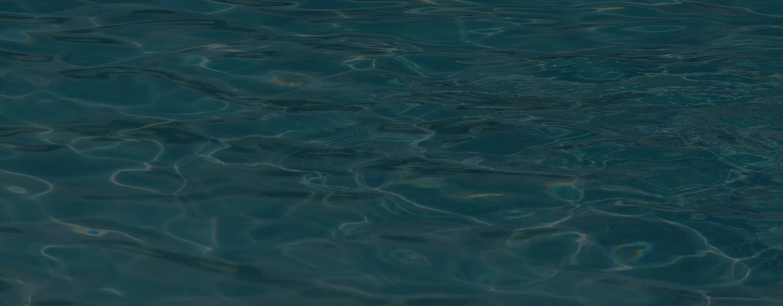 Serene view of a shimmering blue swimming pool with gentle ripples creating a peaceful ambiance.