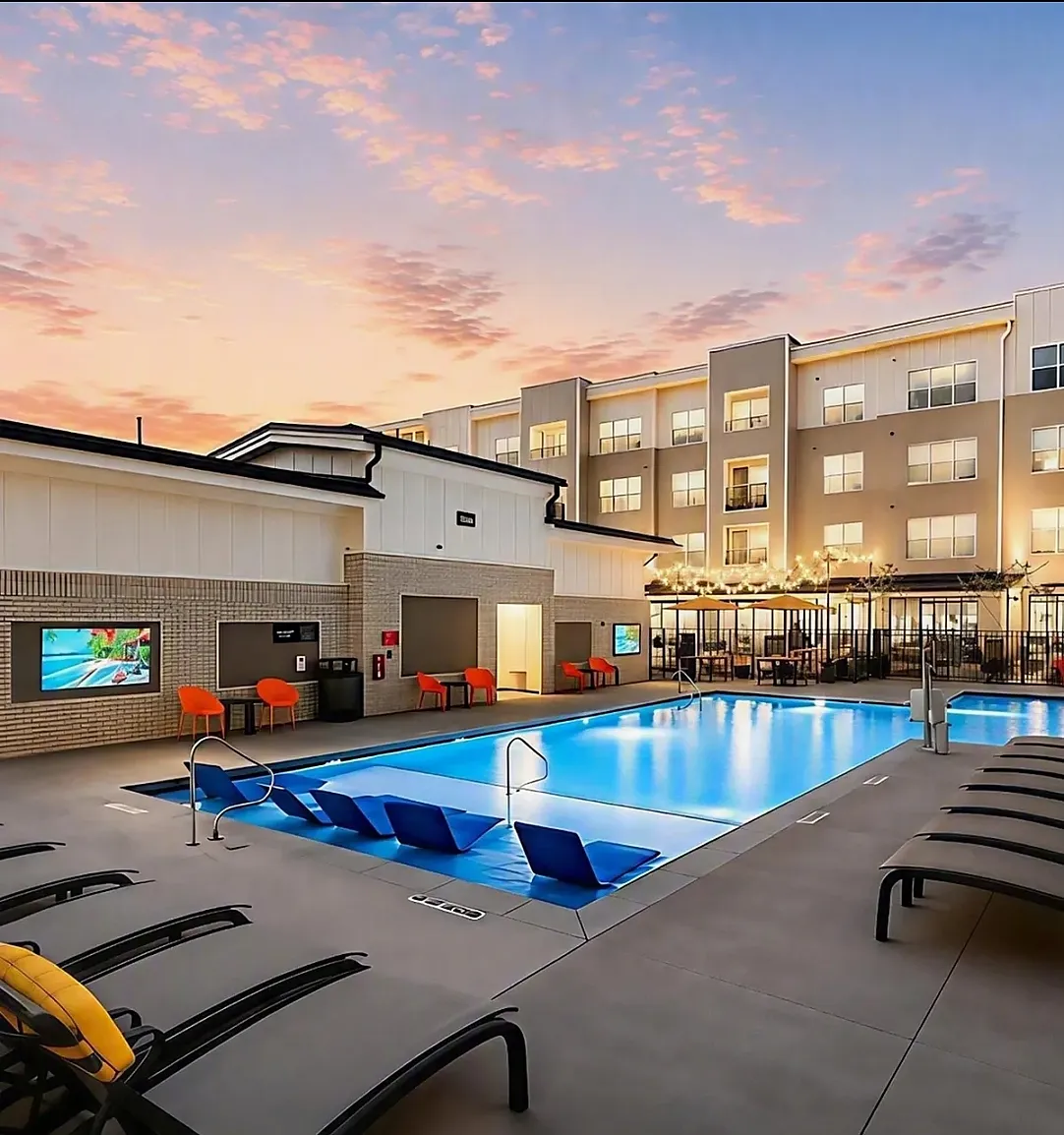 Resort-style pool at Abberly Commons in Raleigh, NC, with lounge seating, shaded umbrellas and a beautifully lit courtyard.