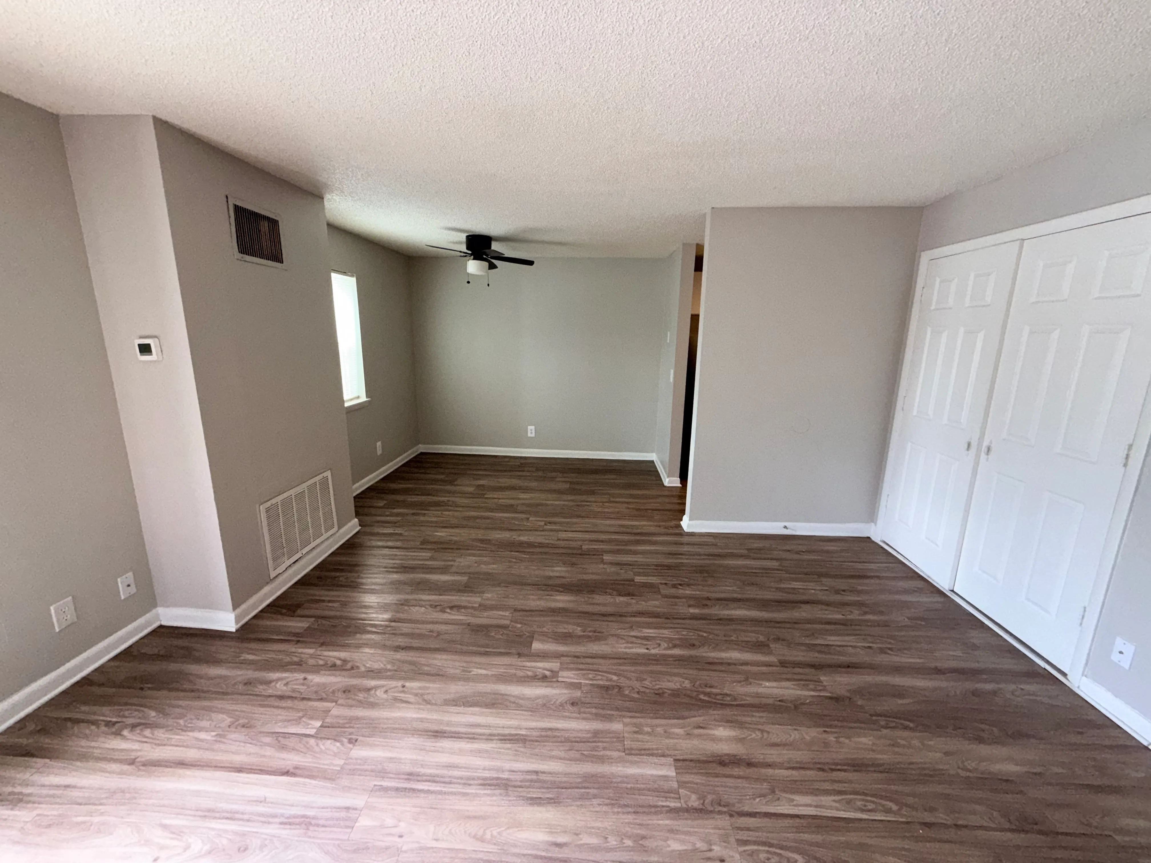 Modern living area with sleek hardwood floors, neutral walls, and ample natural light, perfect for stylish interiors.