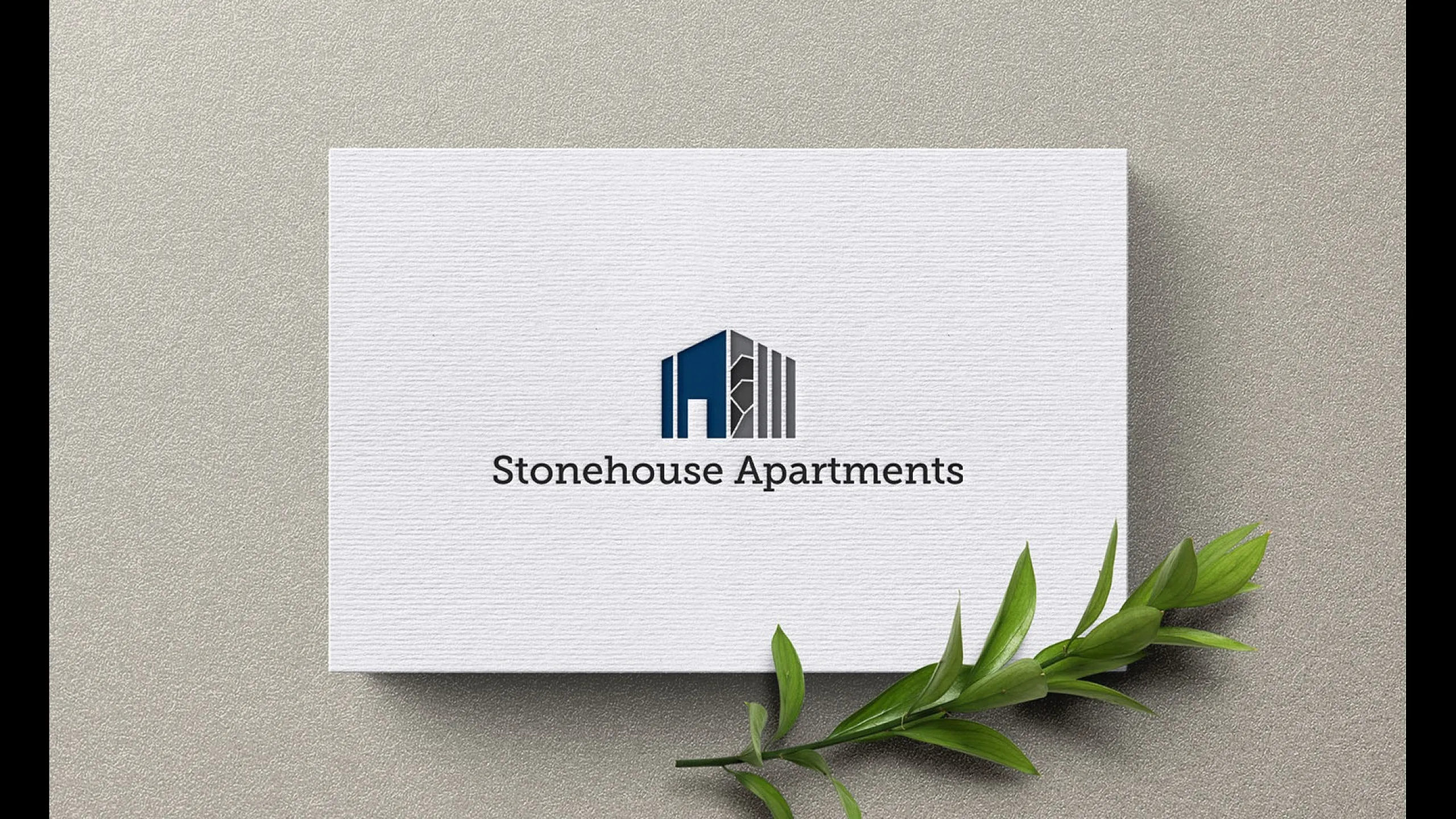 Elegant logo design for Stonehouse Apartments with a modern building silhouette on textured paper, complemented by a fresh green leaf accent.