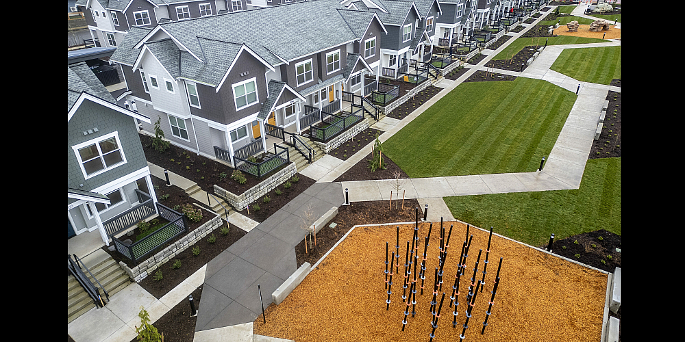 Aerial view of a picturesque townhouse community with landscaped lawns and modern homes.