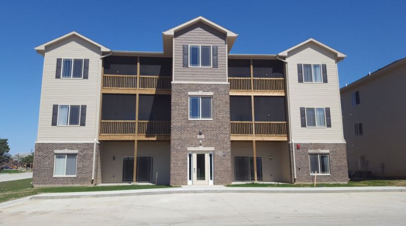 Modern three-story apartment building with stylish brick facade, inviting balconies, and ample window views on a sunny day.