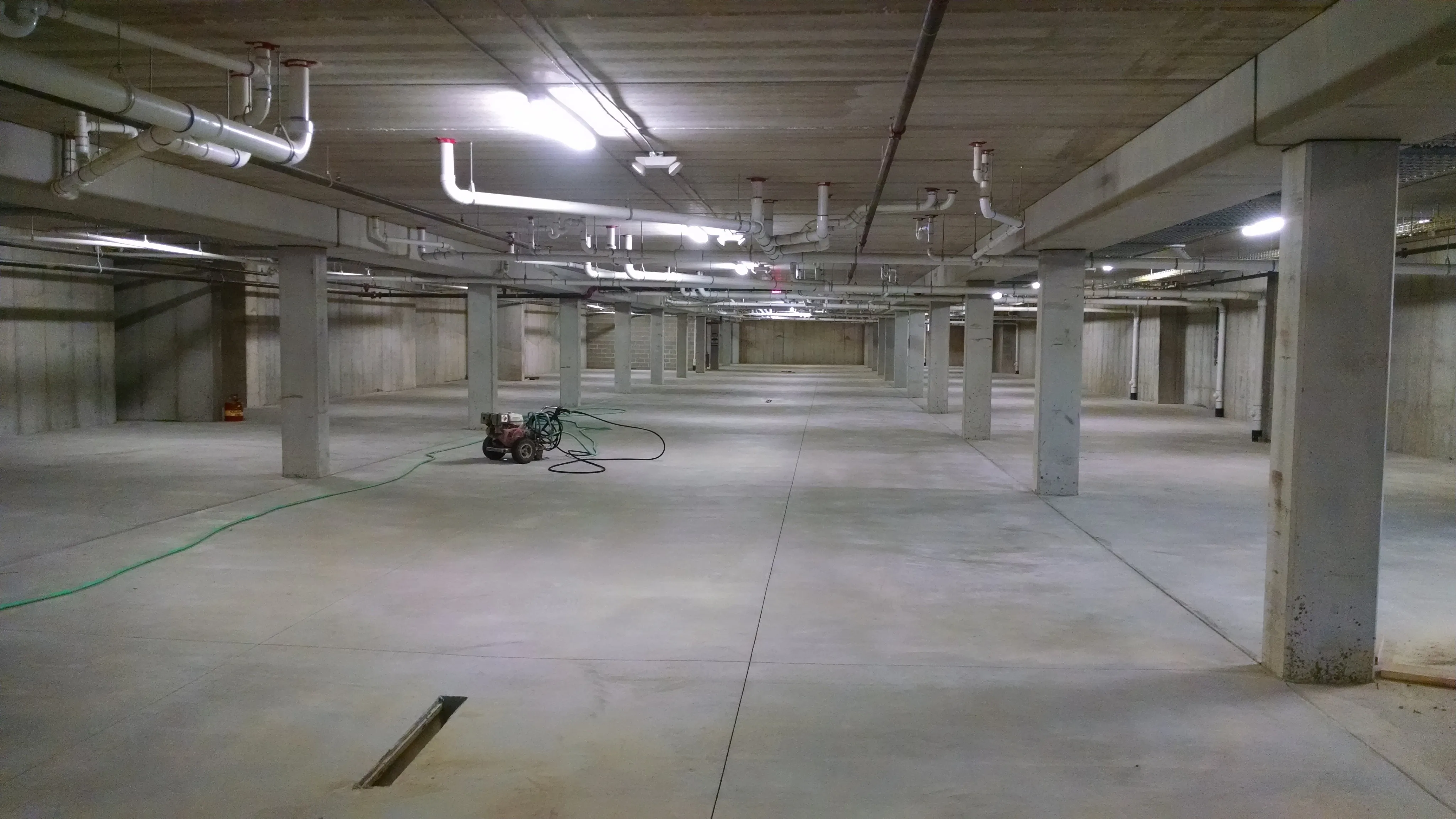underground parking area with robust concrete pillars and bright overhead lighting, offering ample space for multiple vehicles.